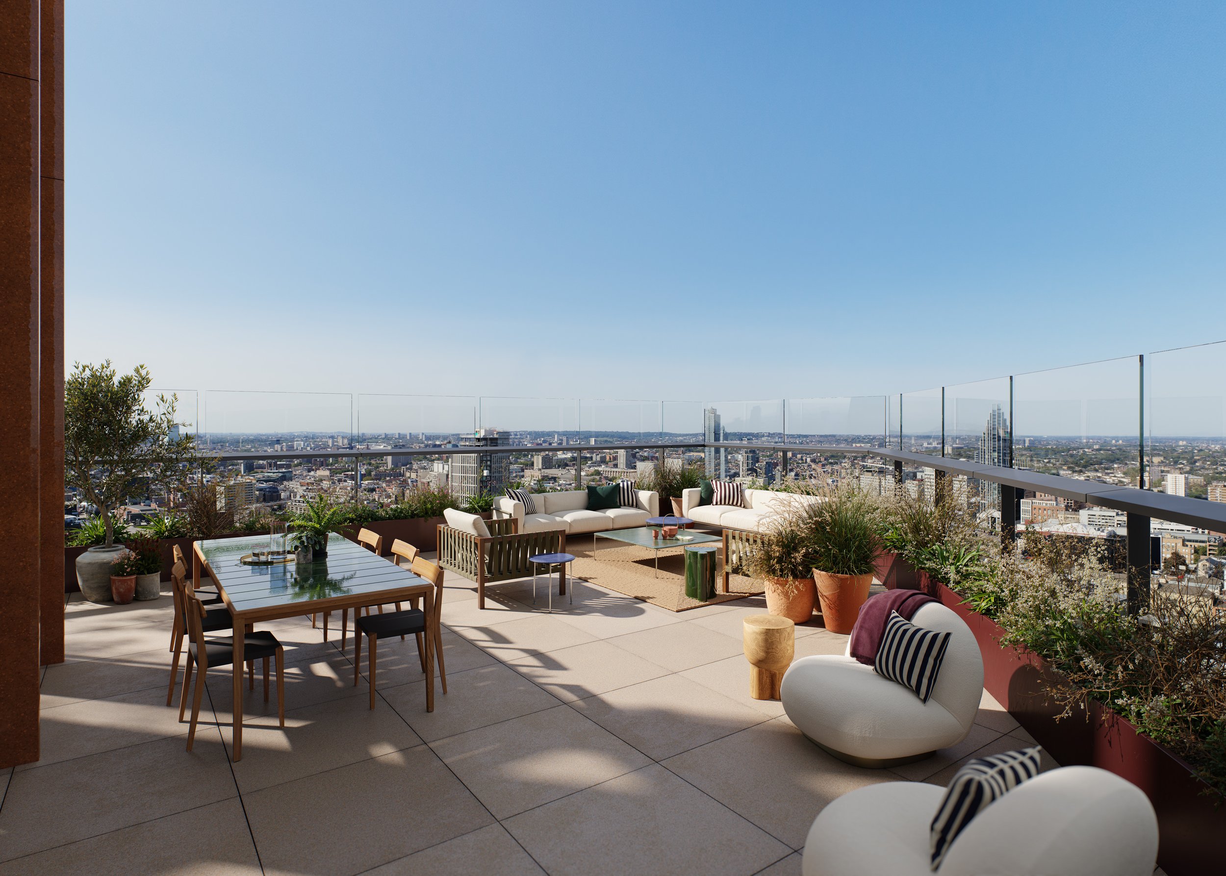 City skyline view from a spacious rooftop terrace with outdoor seating, including sofas and chairs, potted plants, and a dining table under a clear blue sky.