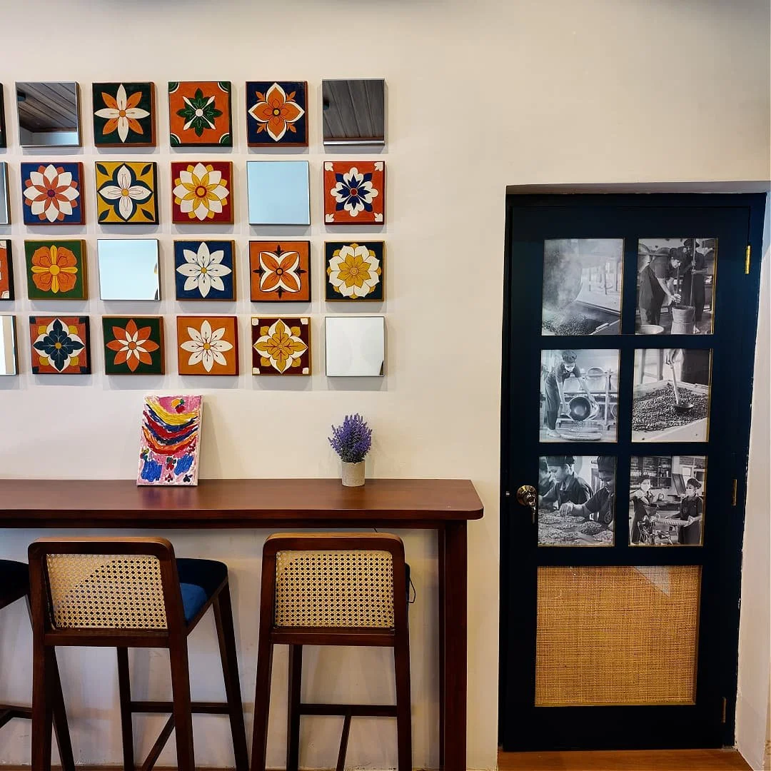 Roseland coffee roasters' first cafe, ceylon kahawa's interior with colourful flower design on the wall, table from wood and door with photos in black and white of the employees making coffee
