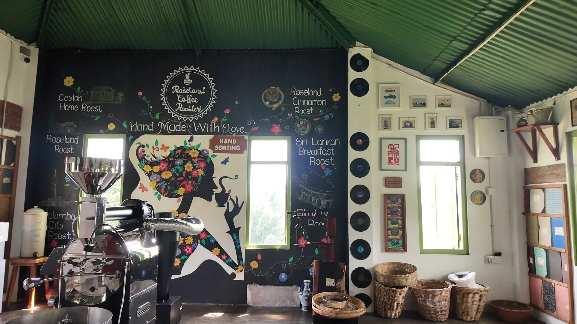 Roseland coffee roaster's factory and bar with a coffee machine in the middle, a black artsy wall explaining the hand-made coffee and woven baskets with coffee beans in sri lanka