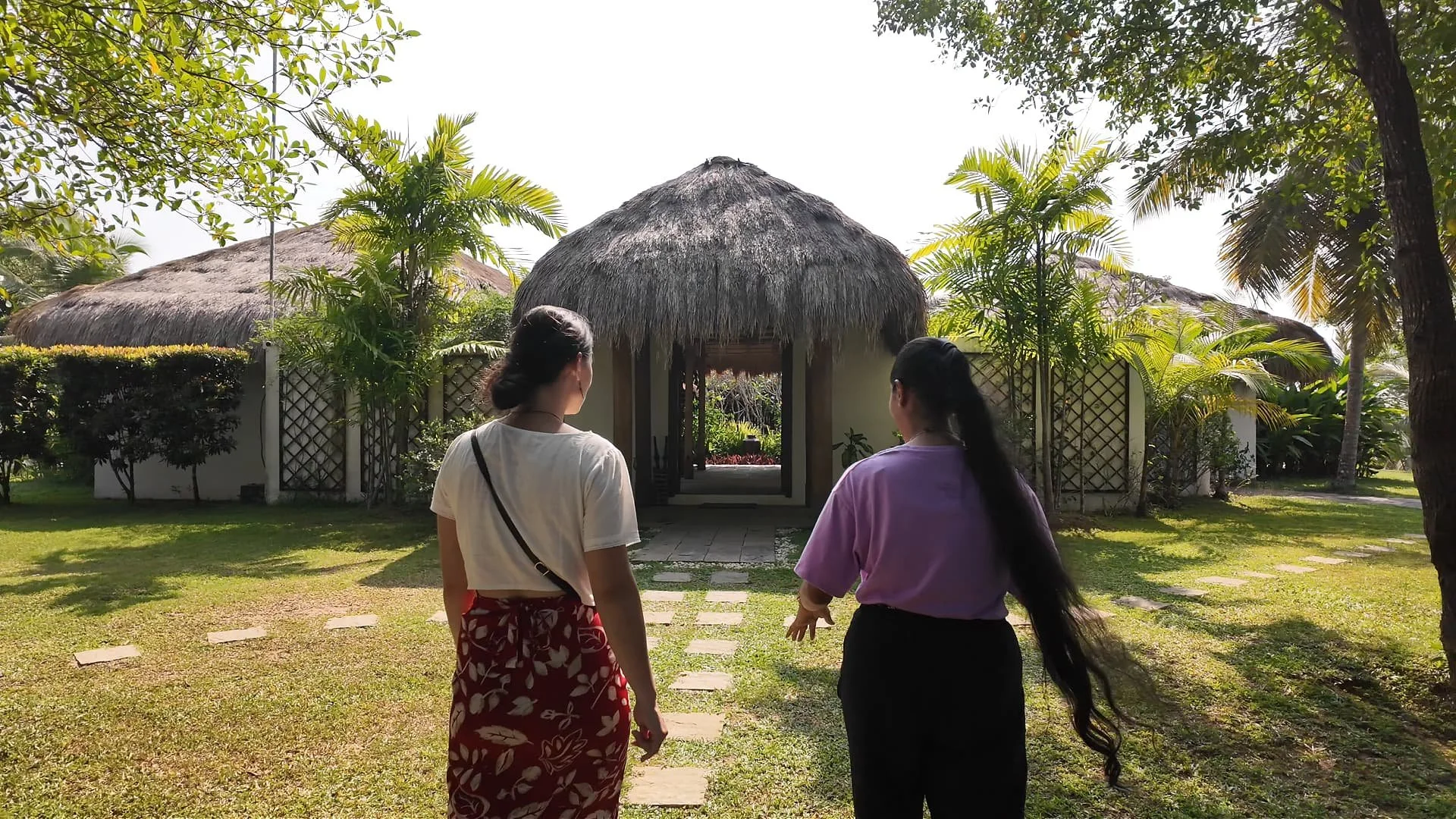 standing in front of tekanda lodge, a beautiful white stone lodge with dried grass as a roof