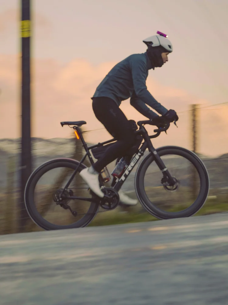 Daniil riding past a wooden fence under a pink sunrise