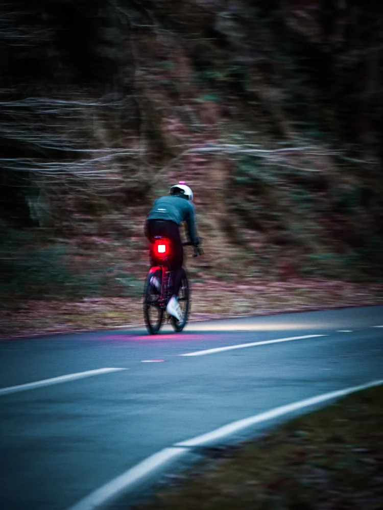 Daniil riding with his rear light on, the trees blurred with motion