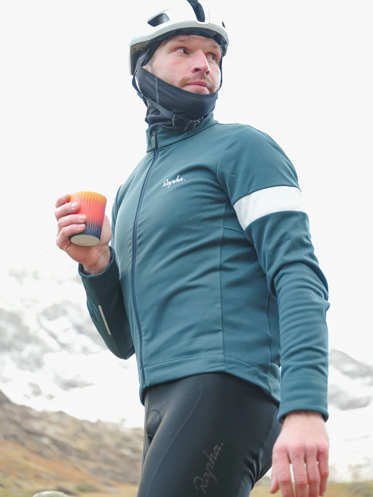 Daniil holding a coffee in the cold, snowy peaks behind him