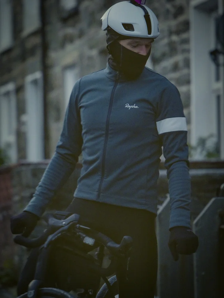 Daniil in a balaclava with his bike on a village street at first light