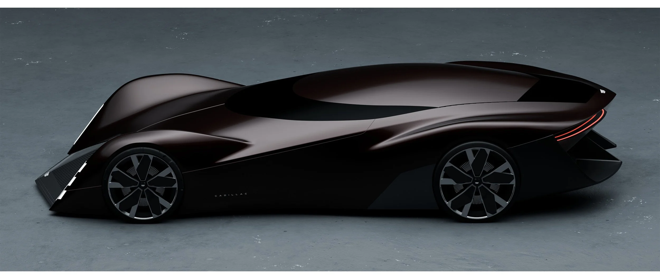 A sleek, futuristic black concept car with aerodynamic design and distinctive wheel rims on a gray surface.