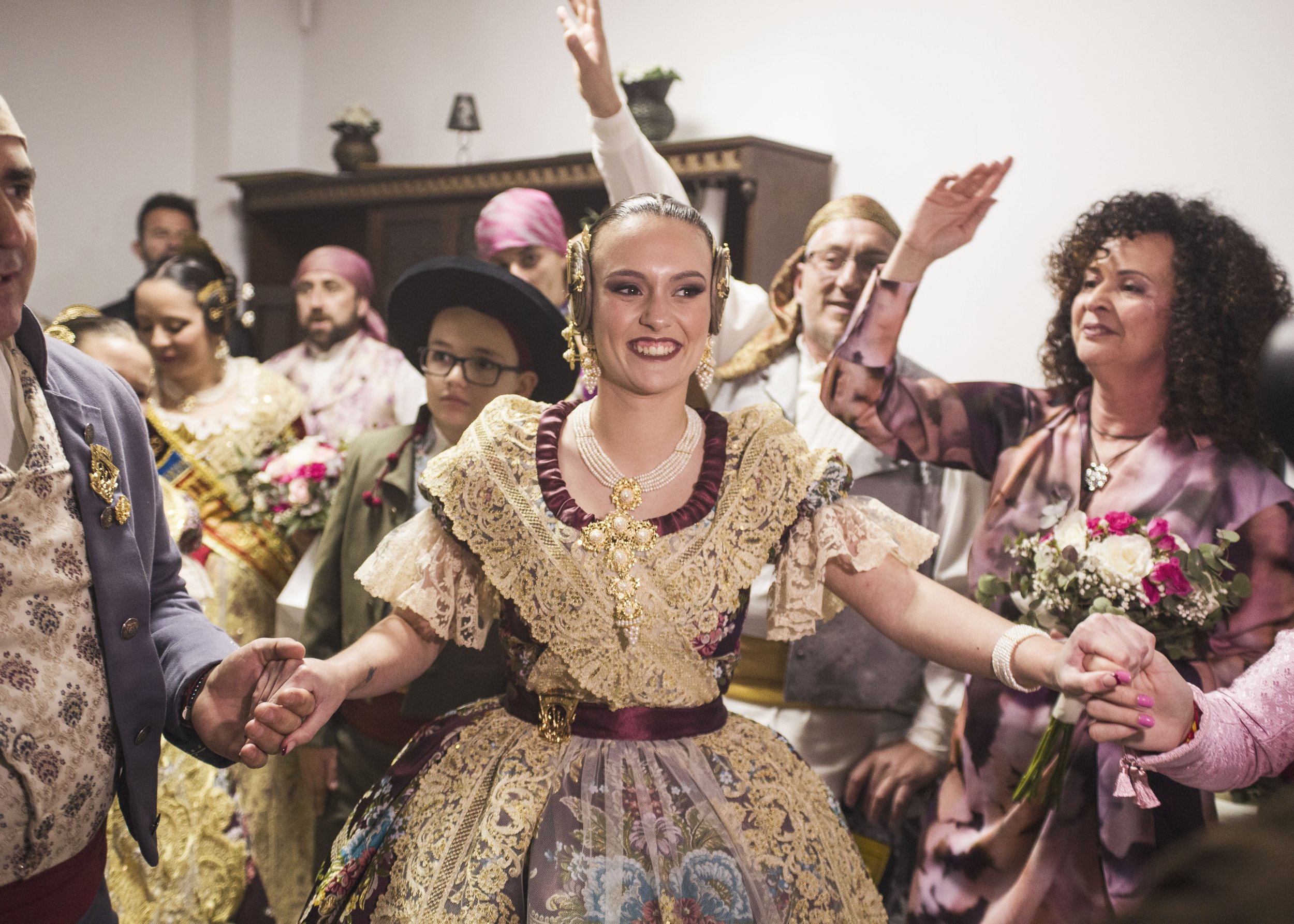 Grupo de personas en celebración, con vestimentas tradicionales y alegres, en el día de la presentación de la fallera mayor.