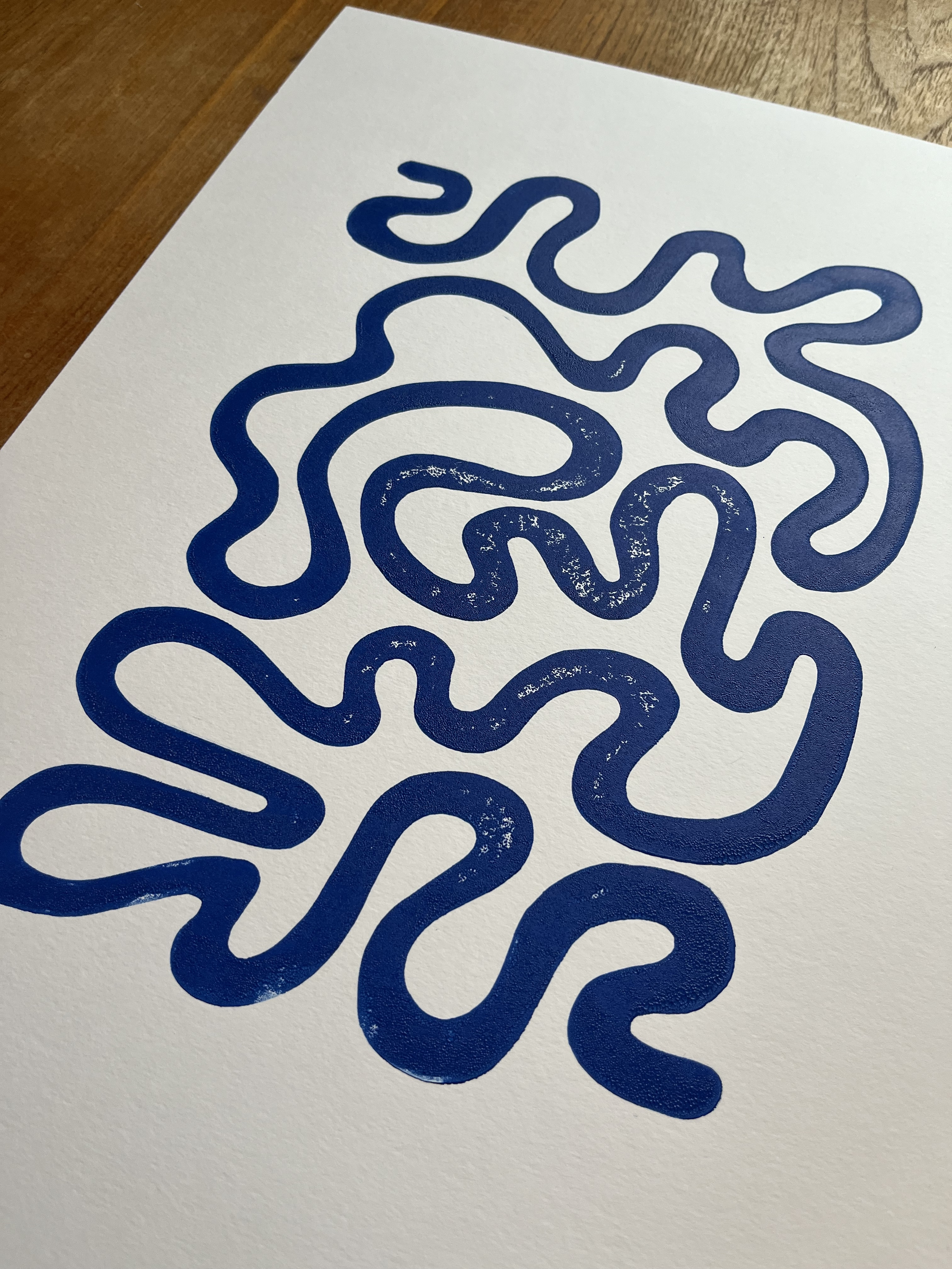 Blue maze on white paper on a wooden surface.
