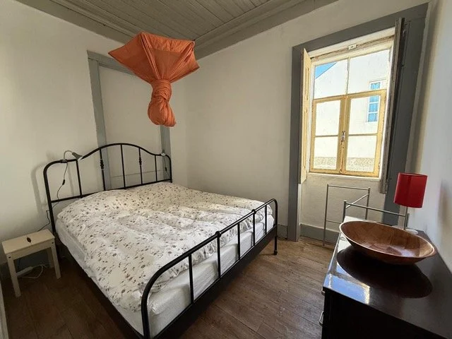 bedroom of a countryside holiday apartment in central Portugal with double bed, window, wooden floor, cabinet, and hanging mosquito net