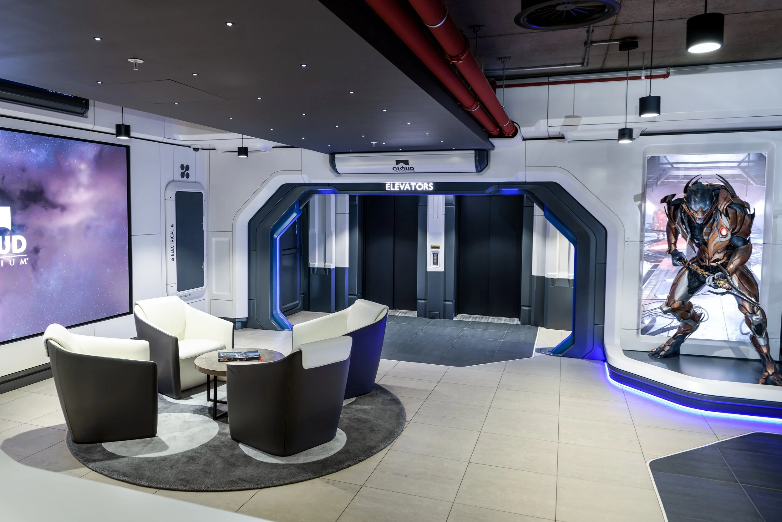 The reception at Cloud Imperium Games’ Manchester headquarters translates the New Babbage aesthetic from the Star Citizen universe into a permanent, operational front-of-house interior.