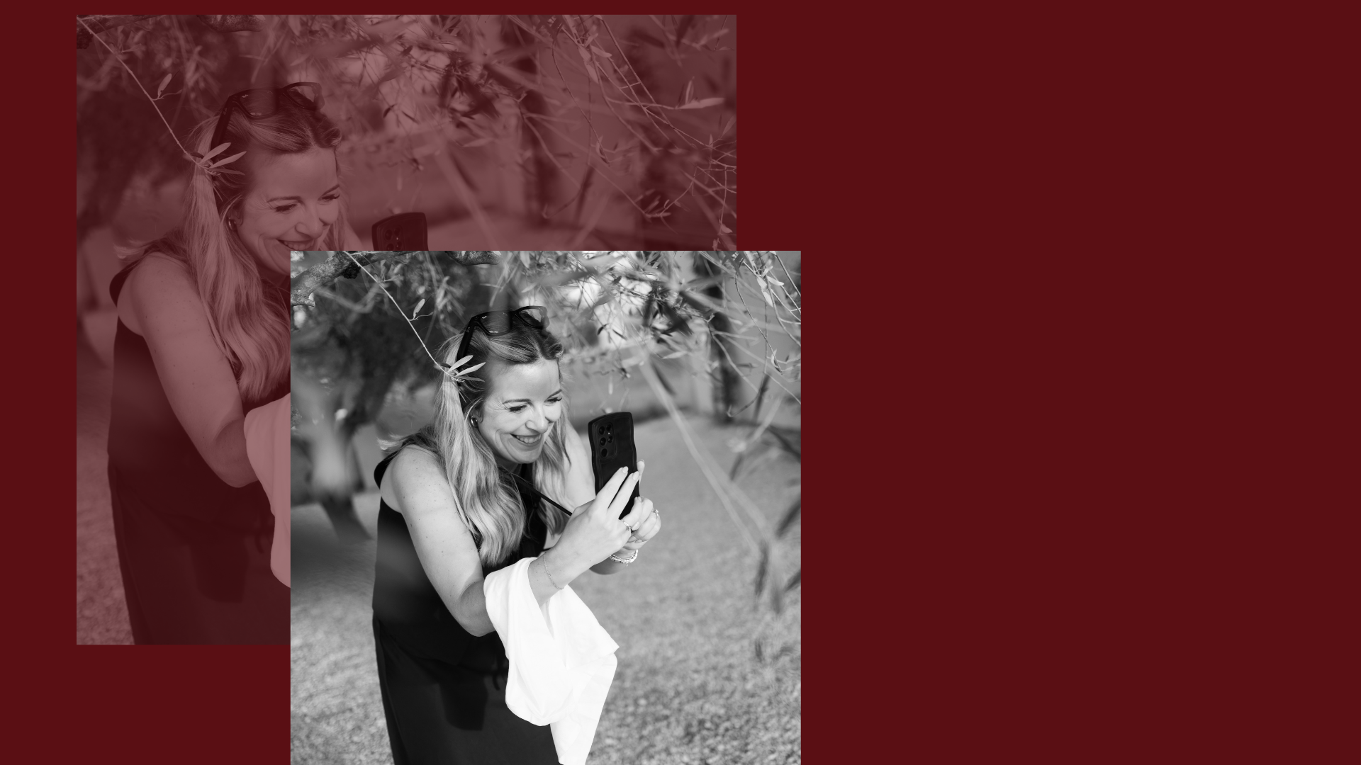 A woman with long wavy hair smiling while looking at her smartphone outdoors, surrounded by trees.