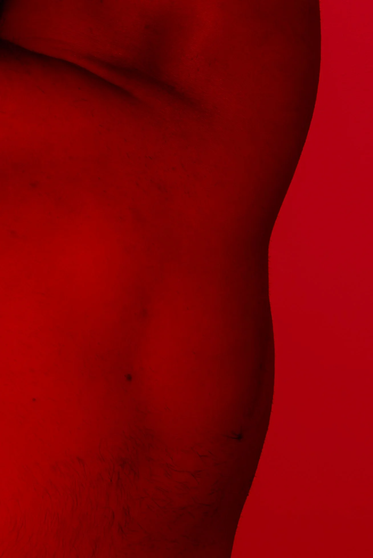 Close-up of a person's arm with visible hair and skin texture on a red background.
