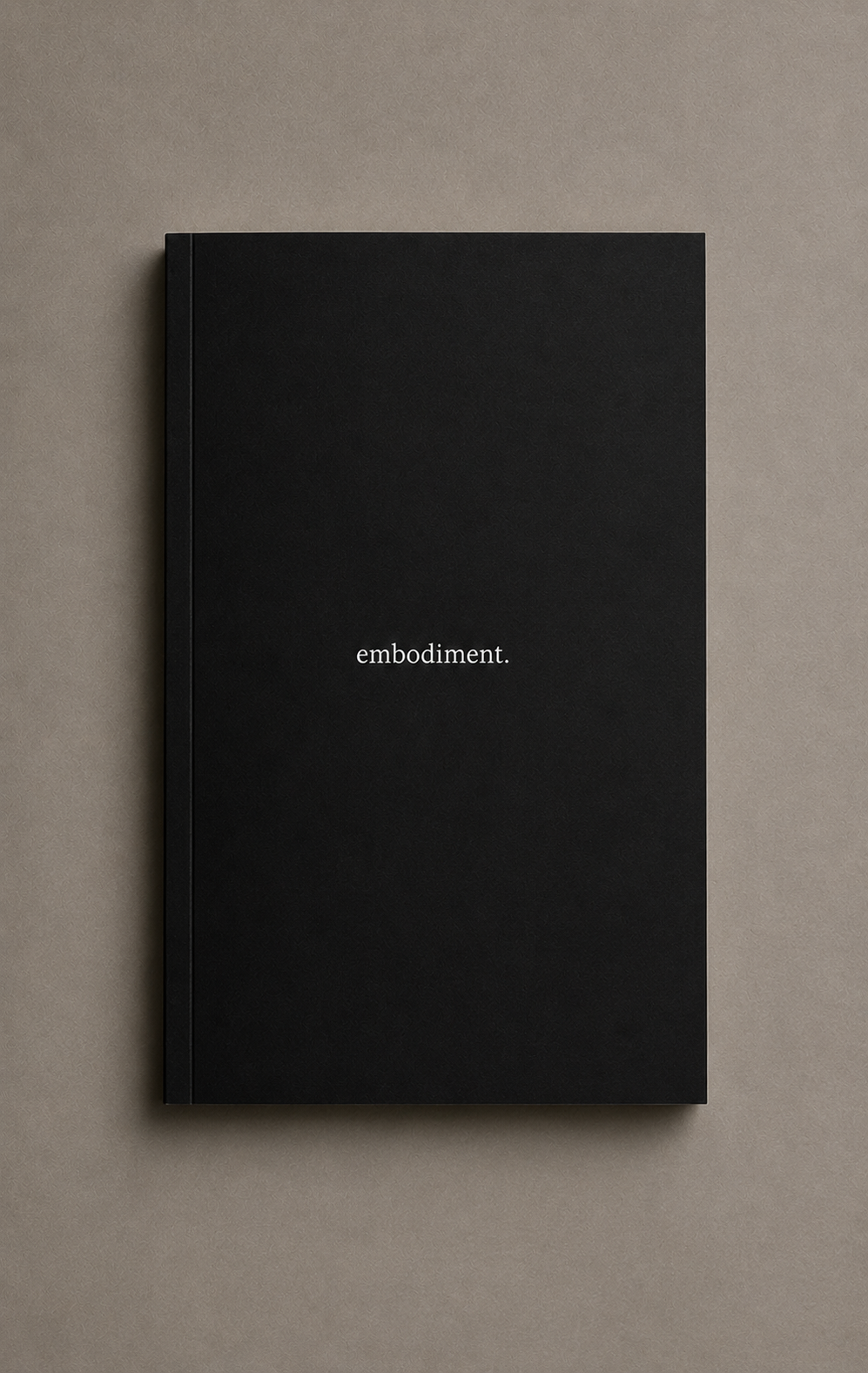 A black hardcover book with the word 'embodiment.' written in white lowercase letters on the cover, placed on a beige surface.