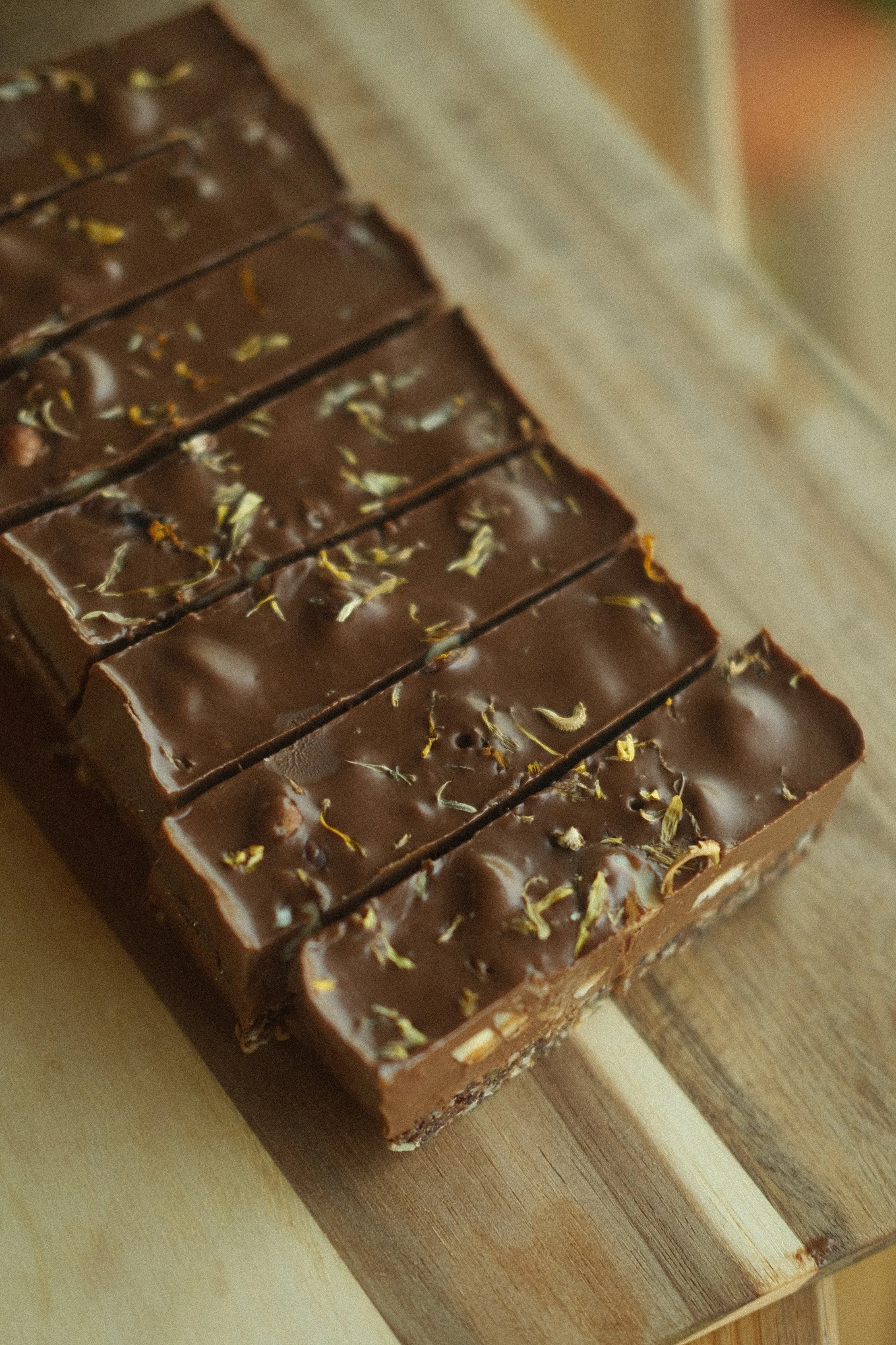 A chocolate bar with toppings on a wooden surface.