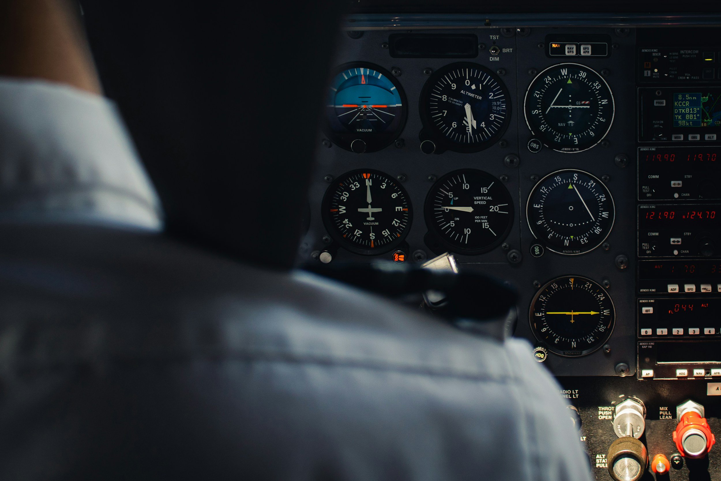 Close-up of an aircraft cockpit instrument panel with various gauges and controls, including altitude, speed, and navigation instruments.