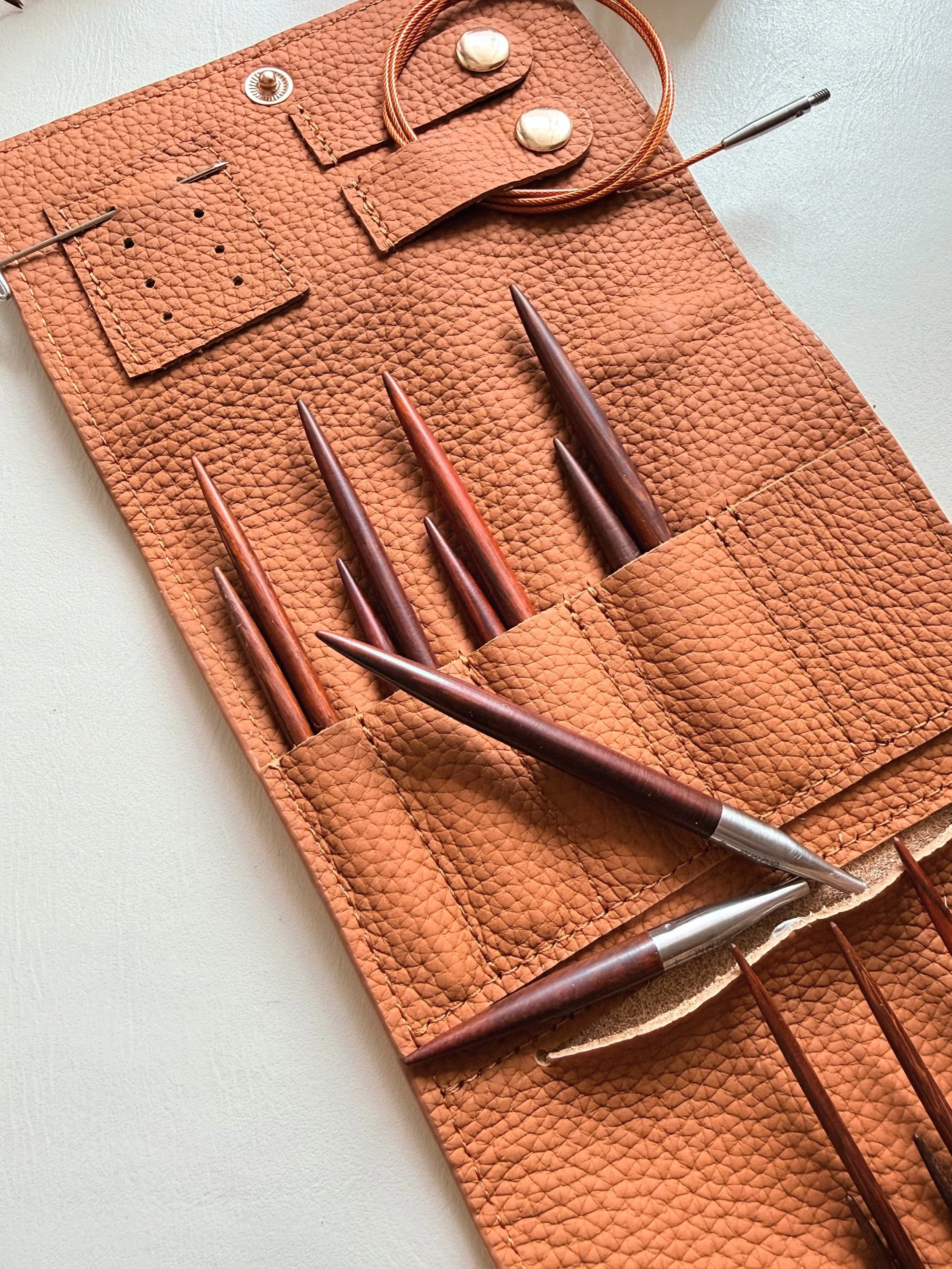 A leather knitting needle organiser with rich colour wooden knitting needles, travel friendly