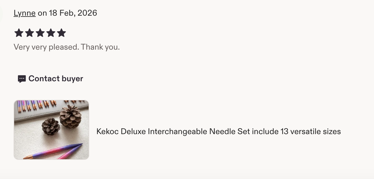 Set of interchangeable knitting needles in various sizes, several colored pens, and two pinecones on a white surface.