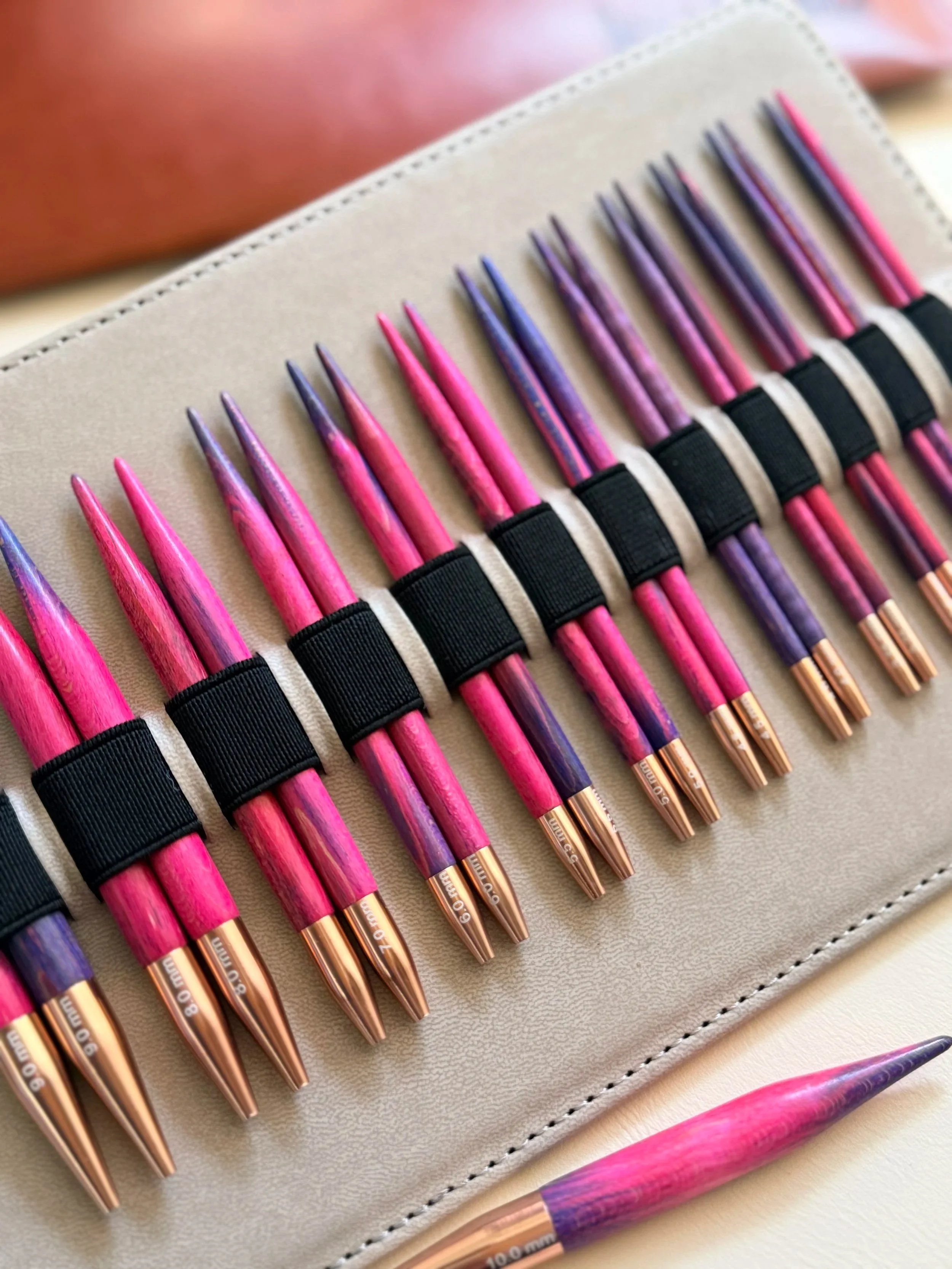 A collection of rainbow handmade wooden interchangeable knitting needles