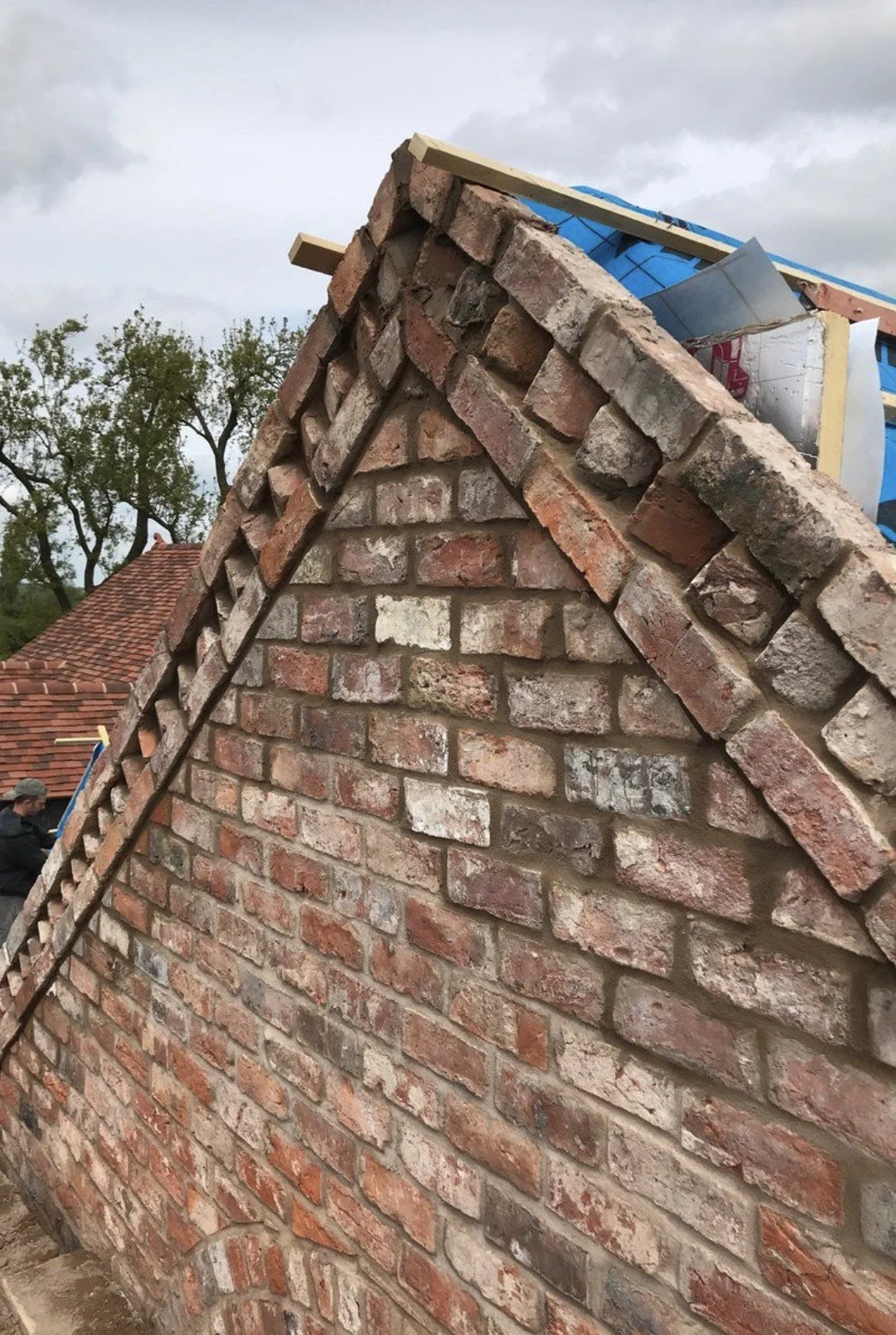 Close-up of a brick wall under construction, with some bricks and roofing materials visible at the top.