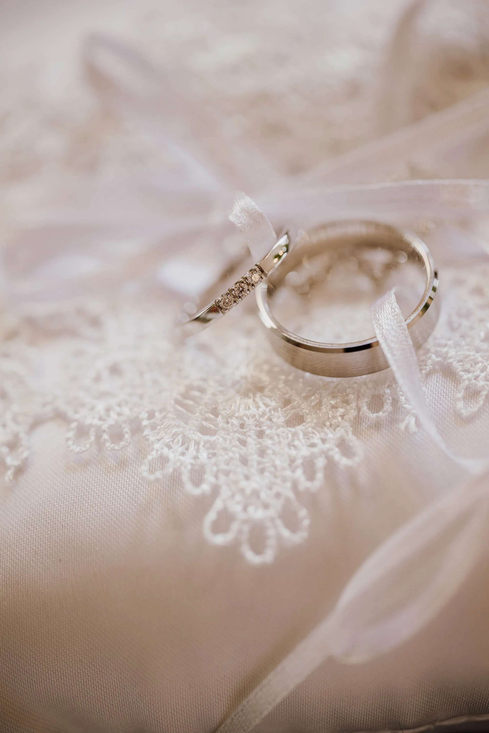 Verlobungsring und Ehering liegen auf Spitze, vermutlich auf Brautkleid.