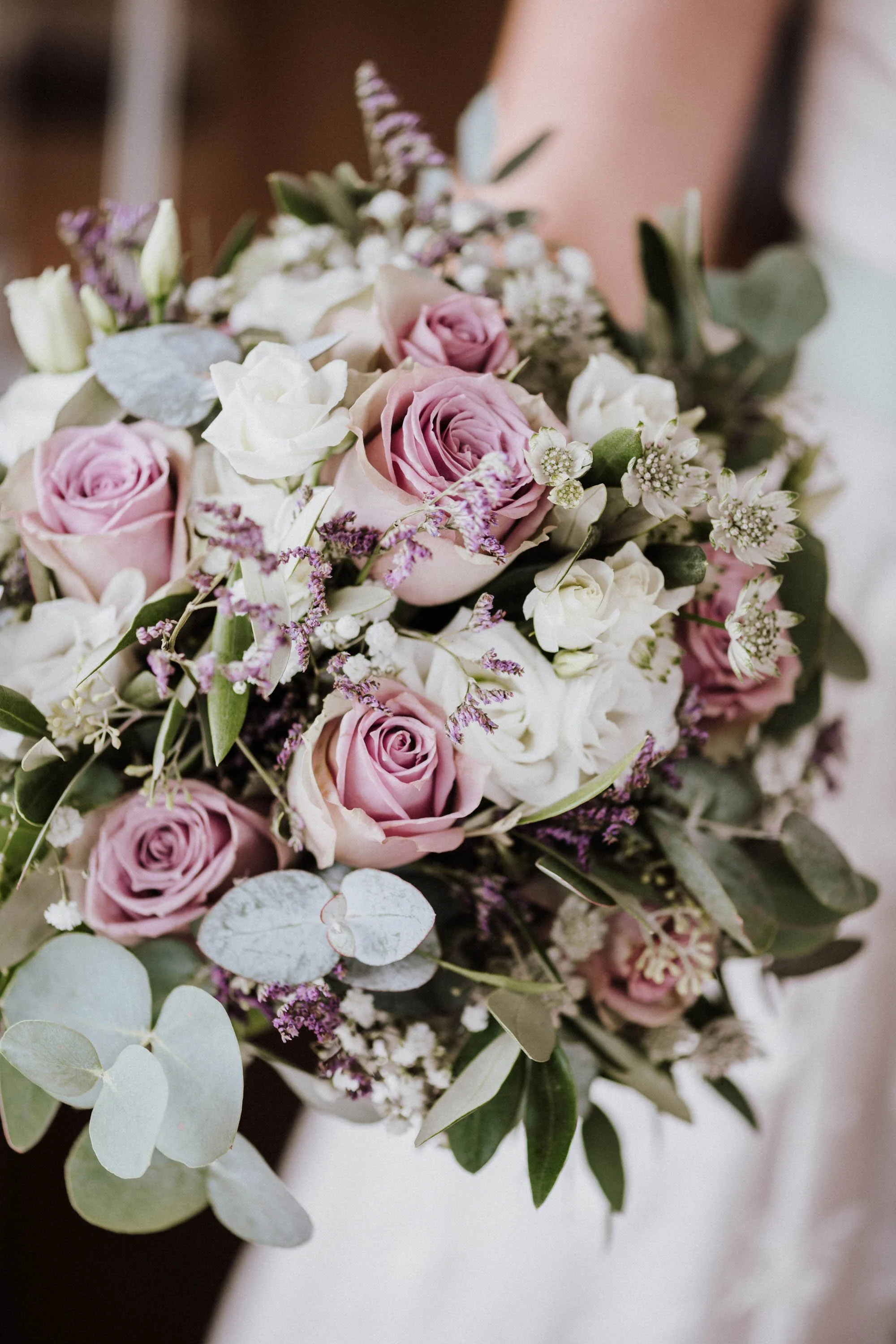Blumenstrauß mit pinken Rosen, weißen Blumen und grünem Laub.