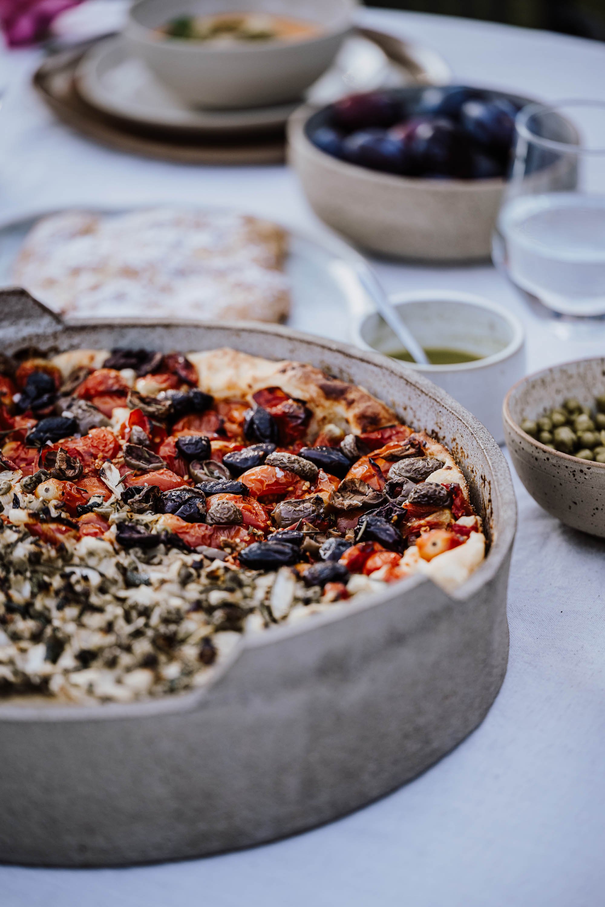 Hübsch angerichtete Kürbissuppe in einer weißen Schale mit Croutons, Petersilie und Kürbiskernen, serviert auf einem grauen Teller.