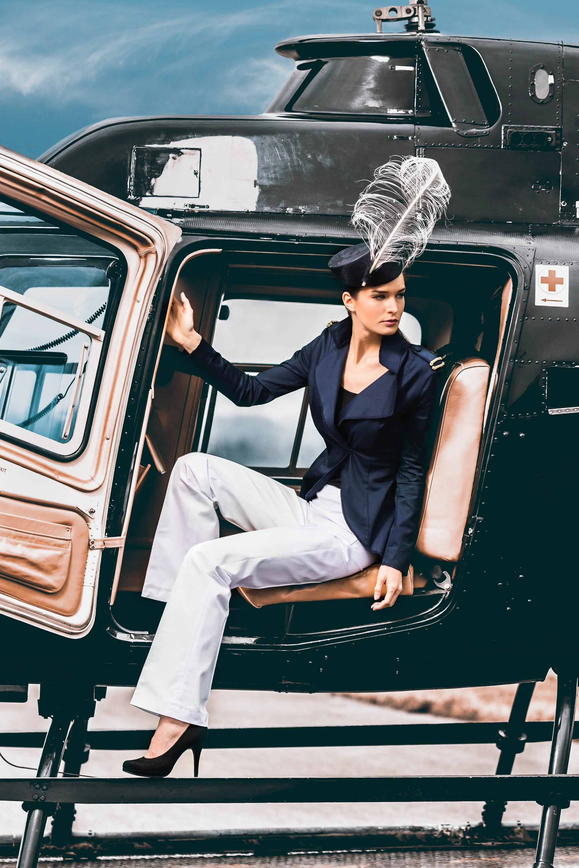 Junge Frau in Polizeiuniform mit Frackmütze mit Feder sitzt in einem Hubschrauber, während sie nach vorne schaut.