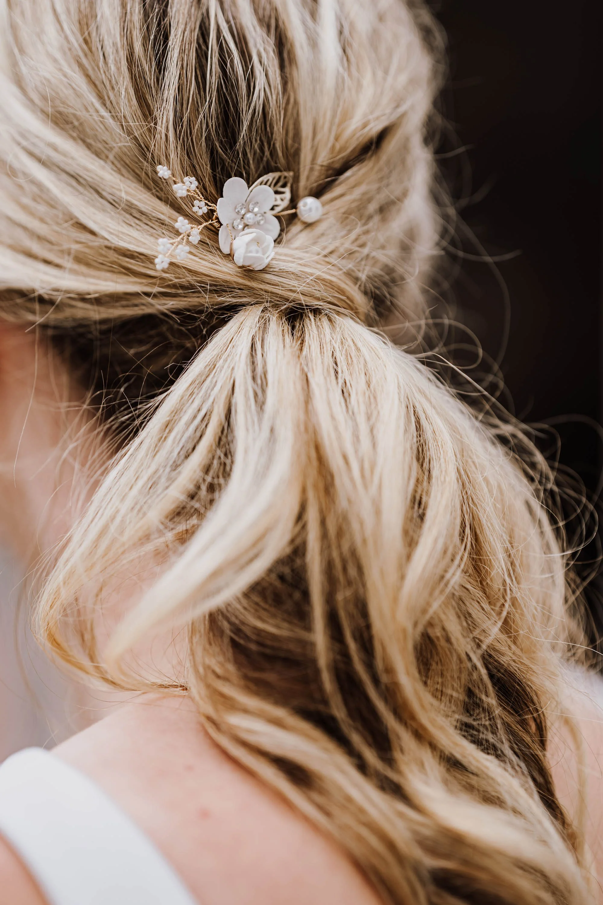 Nahaufnahme eines Damenhairstücks mit einem weißen Blumenschmuck und Perlen in Haargummi.