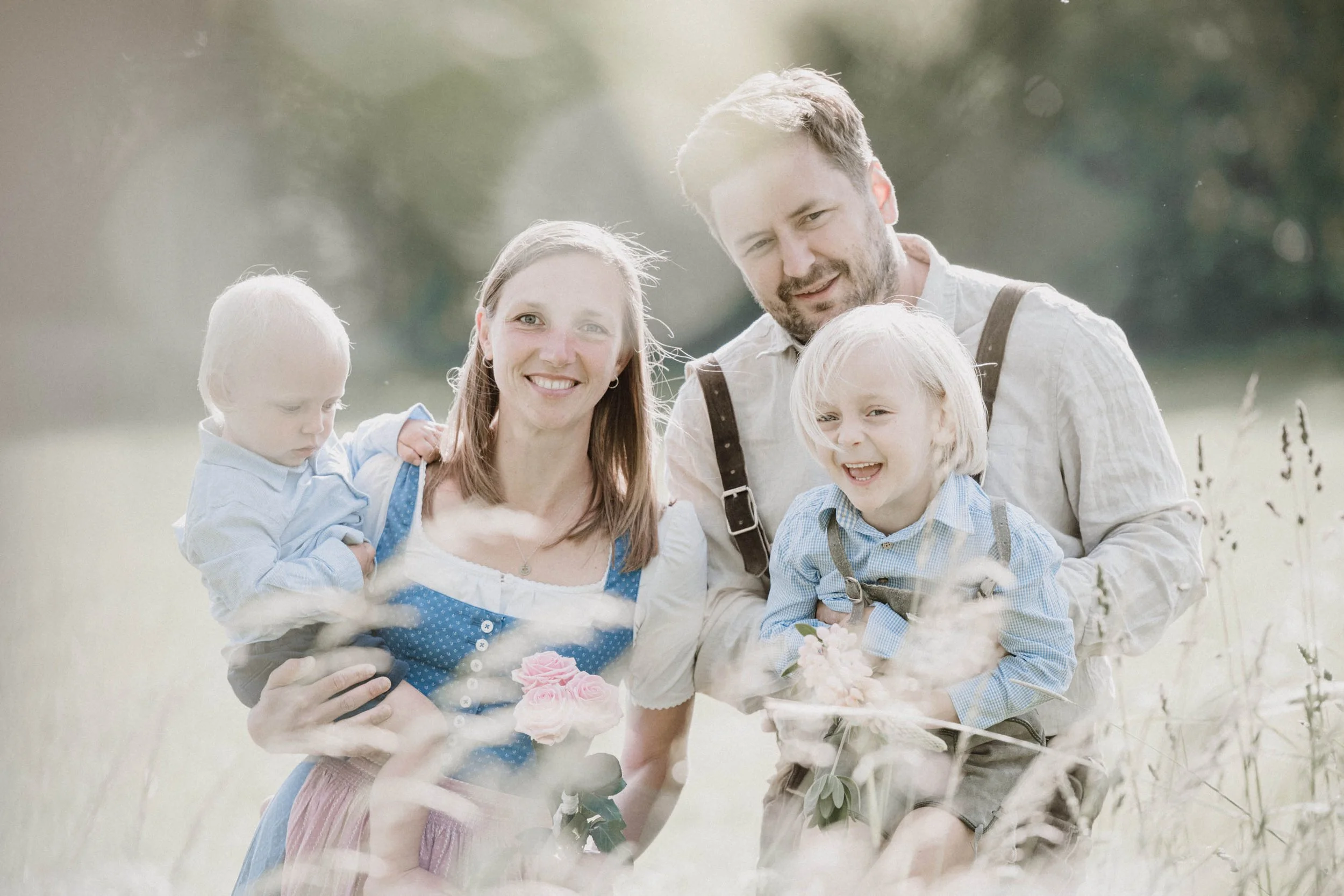 Familie mit zwei Kindern im Freien, die sich an einem sonnigen Tag in der Natur befindet.