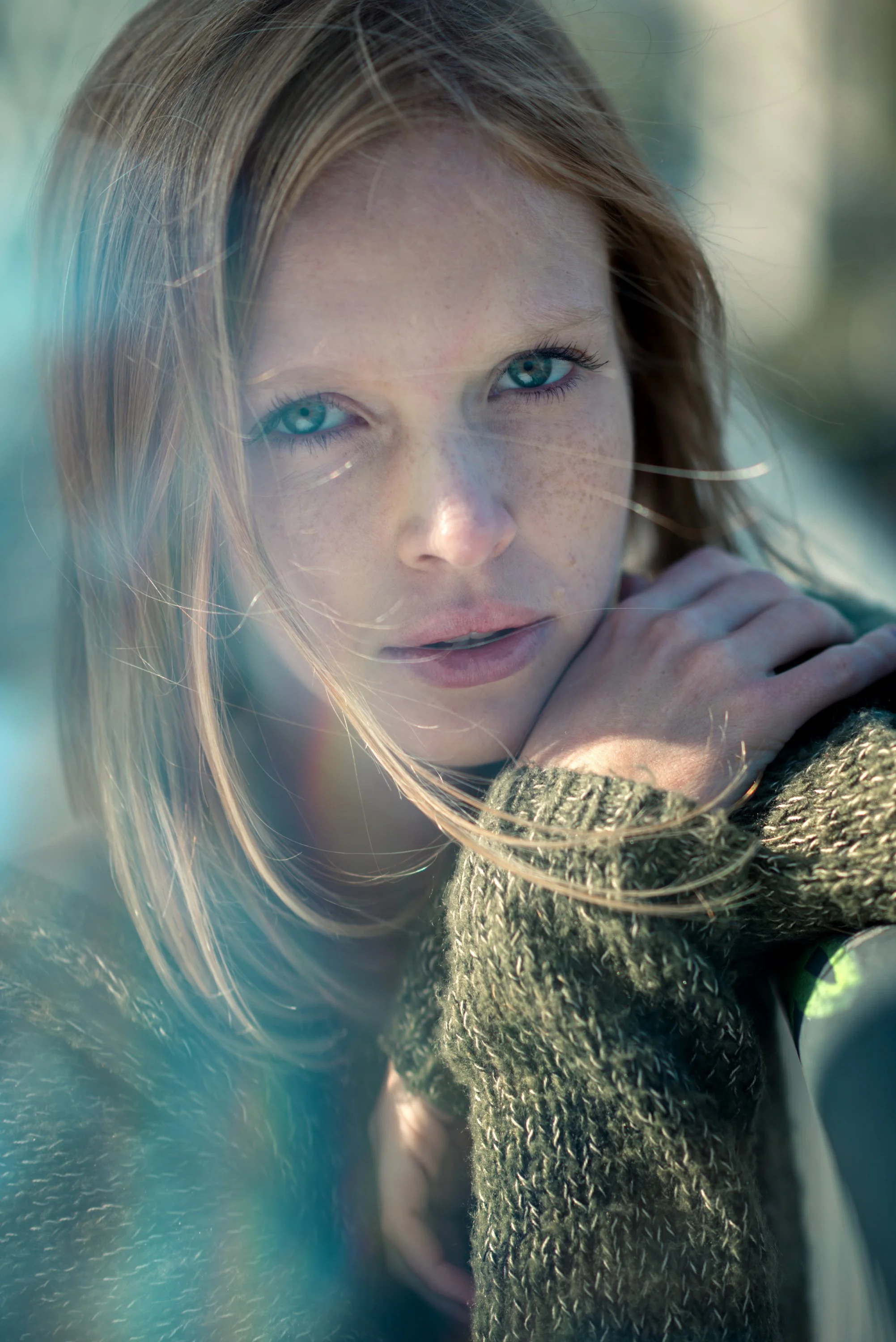 Nahaufnahme eines Mädchens mit blonden Haaren und blauen Augen, das durch ein Fenster schaut.