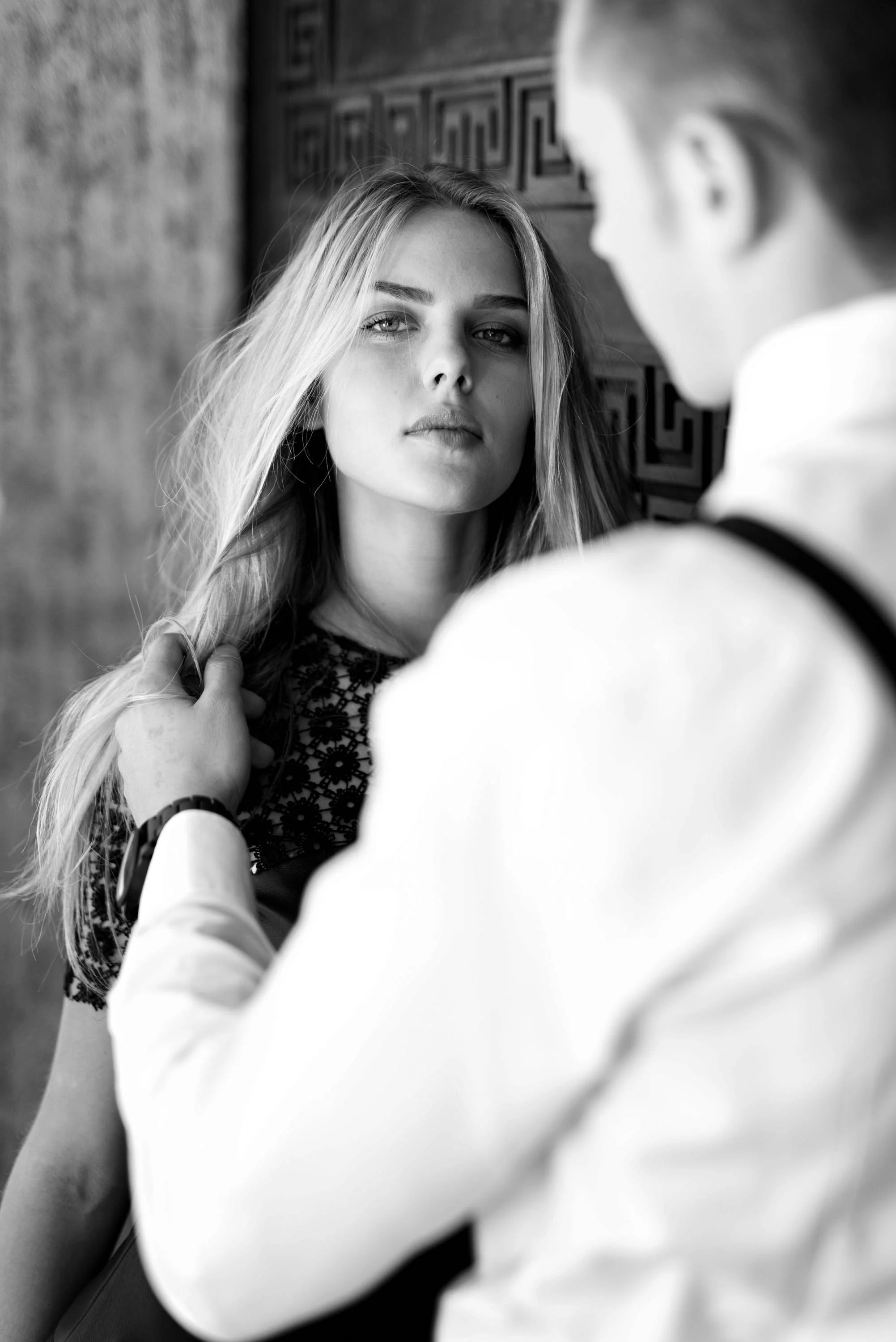 Schwarz-Weiß-Fotografie eines jungen Paares, der Mann hält den Nacken der Frau, sie schaut direkt in die Kamera