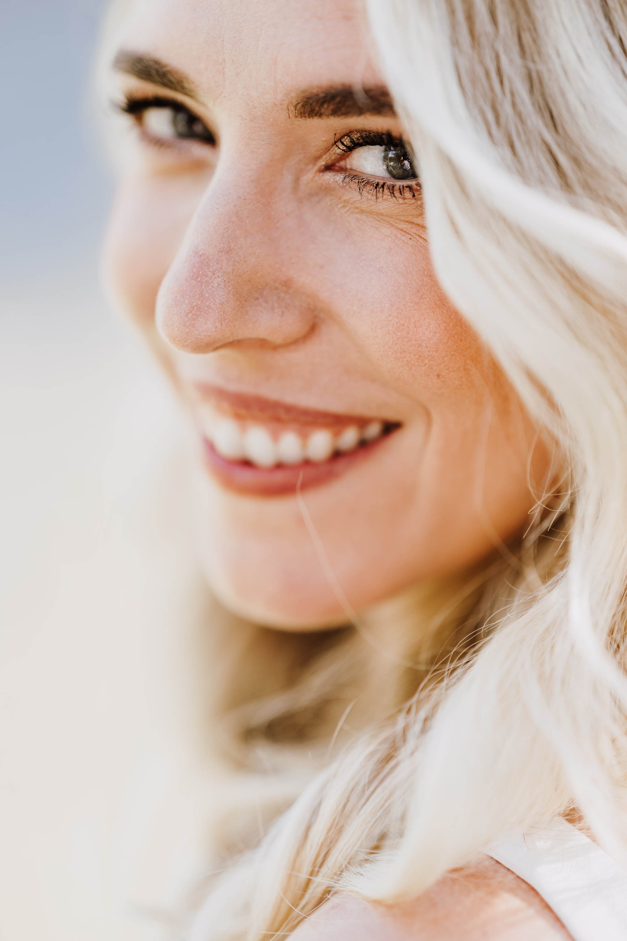 Nahaufnahme eines lachenden jungen Mädchens mit blonden, lockigen Haaren, das in die Kamera lächelt.