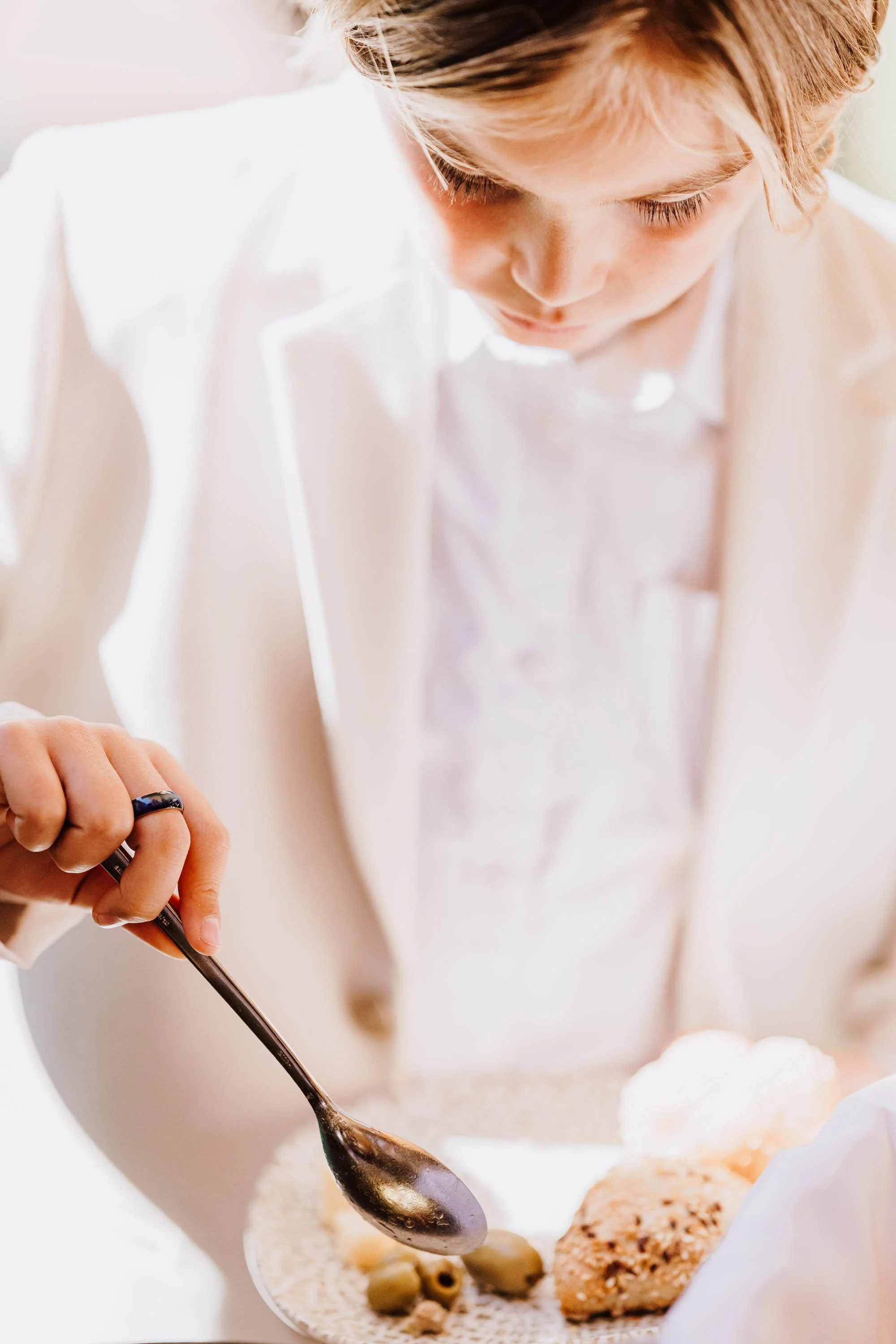 Eine junge Person in einem weißen Hemd, die mit einem Löffel auf einem Teller mit Essen serviert.