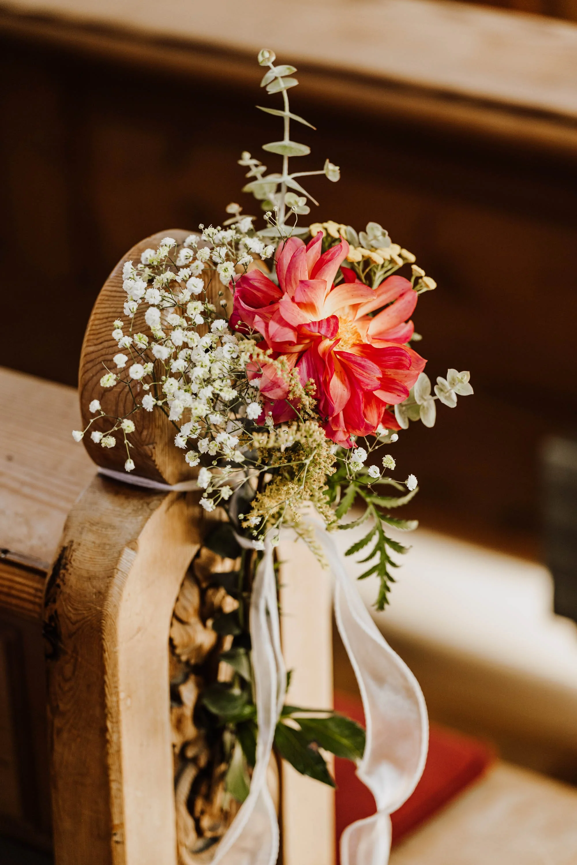 Blumenstrauß mit roten und weißen Blumen, auf Holzbank bei Innenraum