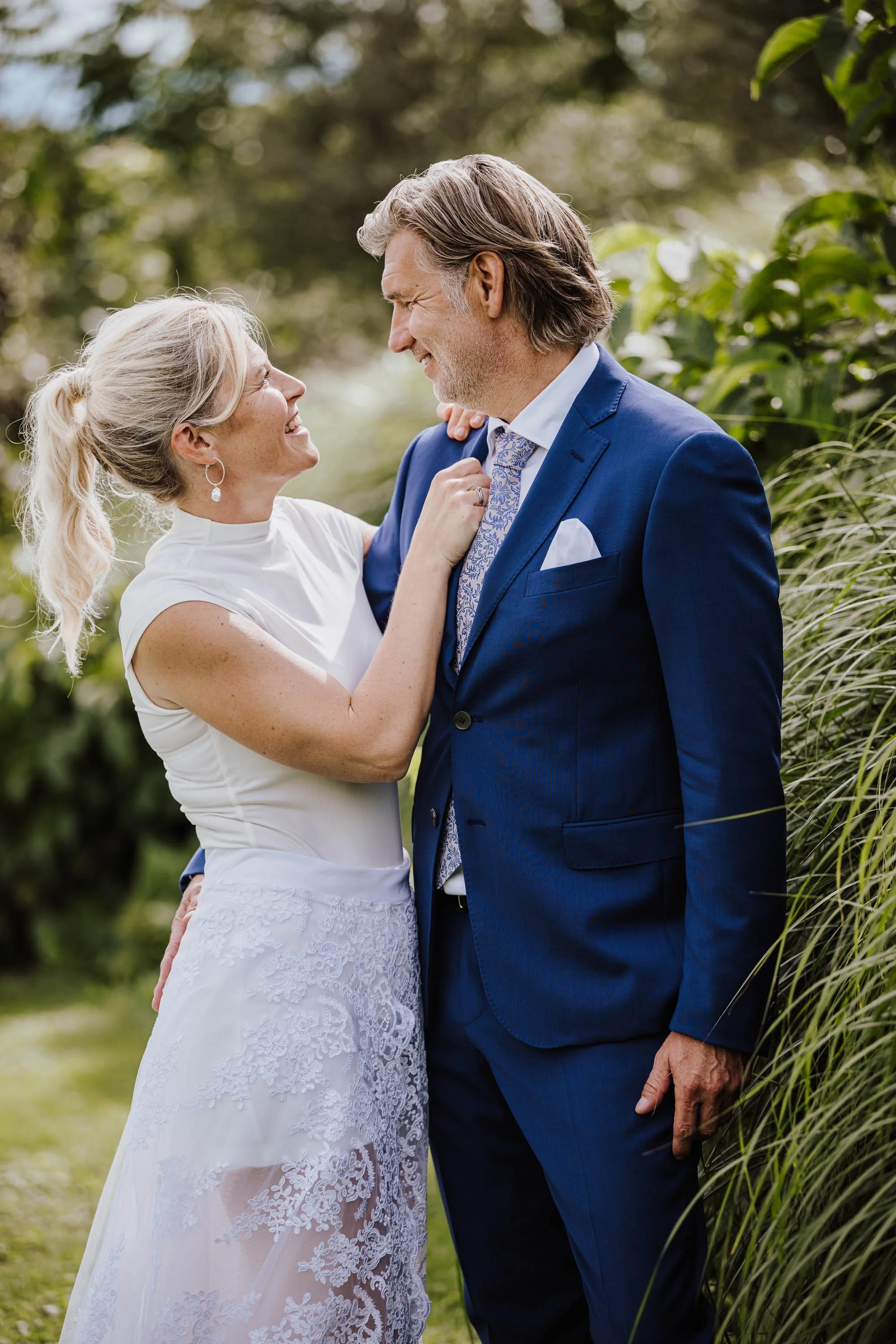 Ein älteres Paar, das bei einem Outdoor-Event fröhlich aussieht, steht sich in der Natur gegenüber, lächelt und genießt den Moment.