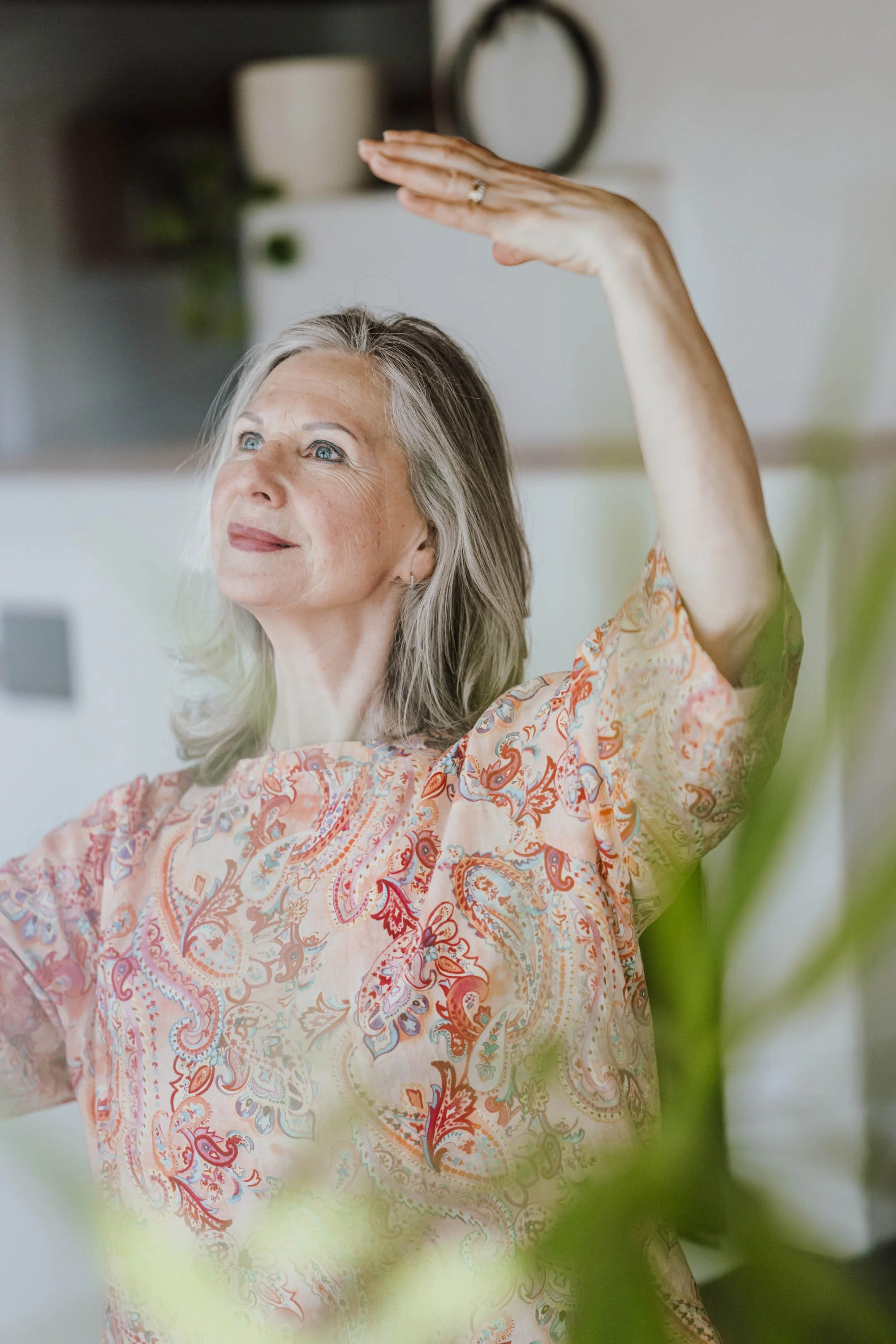 Ältere Frau macht eine Yoga-Übung oder Dehnübung in einem hellen, modernen Raum.