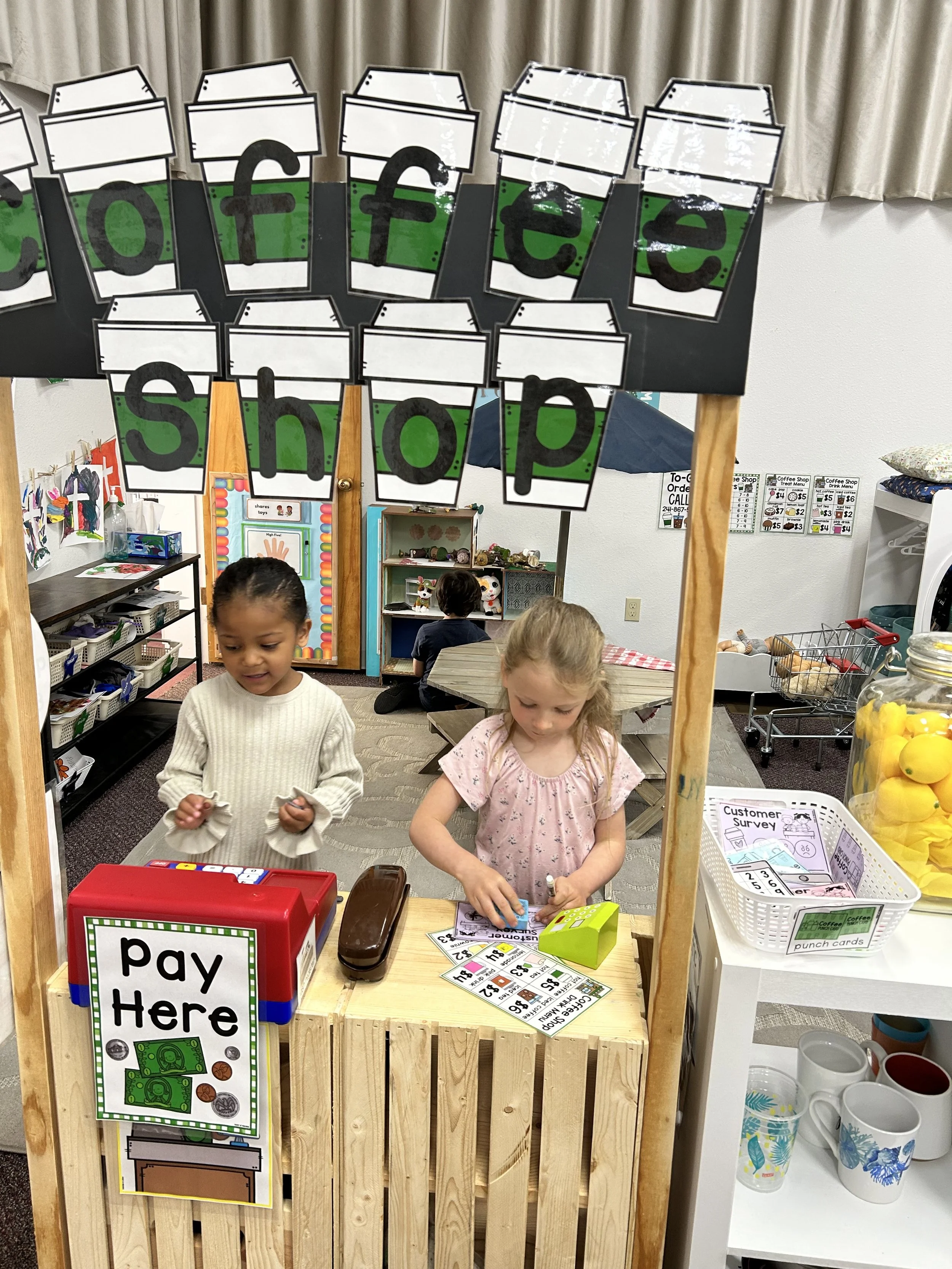 Two preschool girls playing at a pretend coffee shop