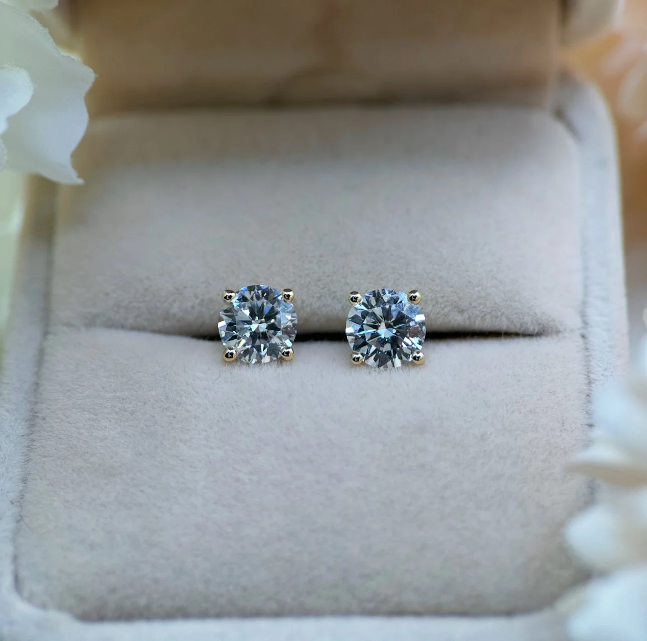 Pair of stud diamond earrings with four prongs in a jewellery box.