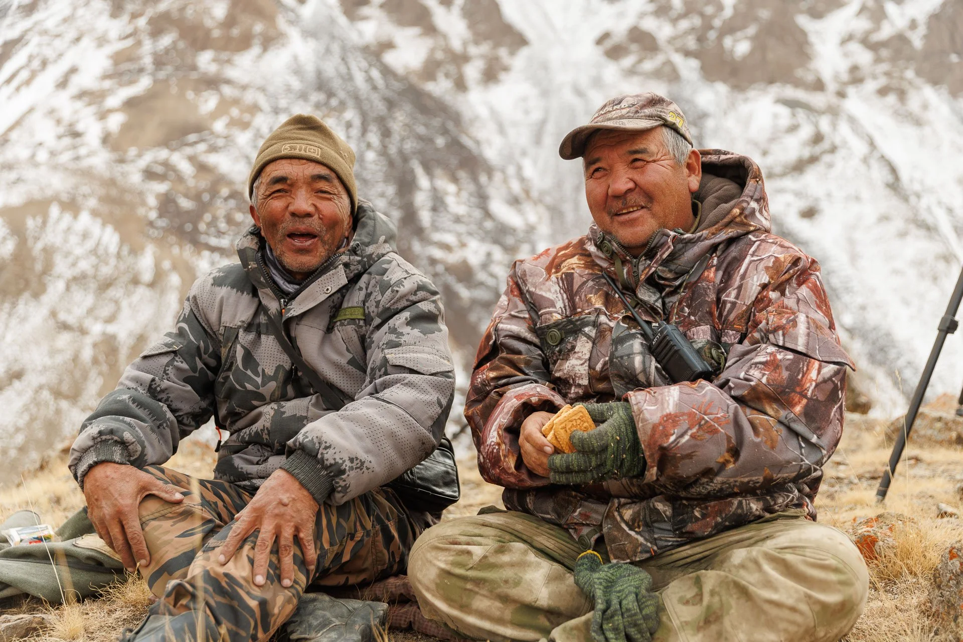Two Kyrgyz men celebrate a snow leopard sighting in Kyrgyzstan