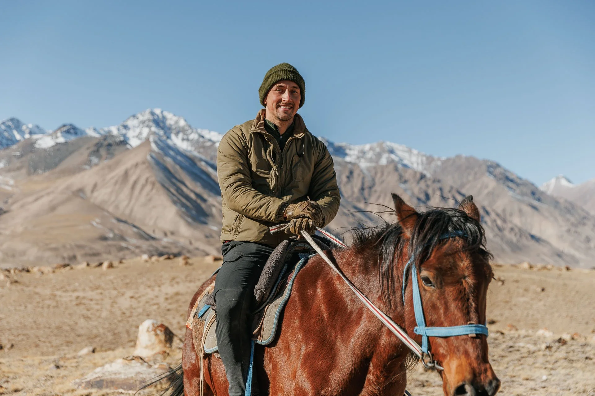 A man on a horse searching for wildlife on a snow leopard holiday in Kyrgyzstan