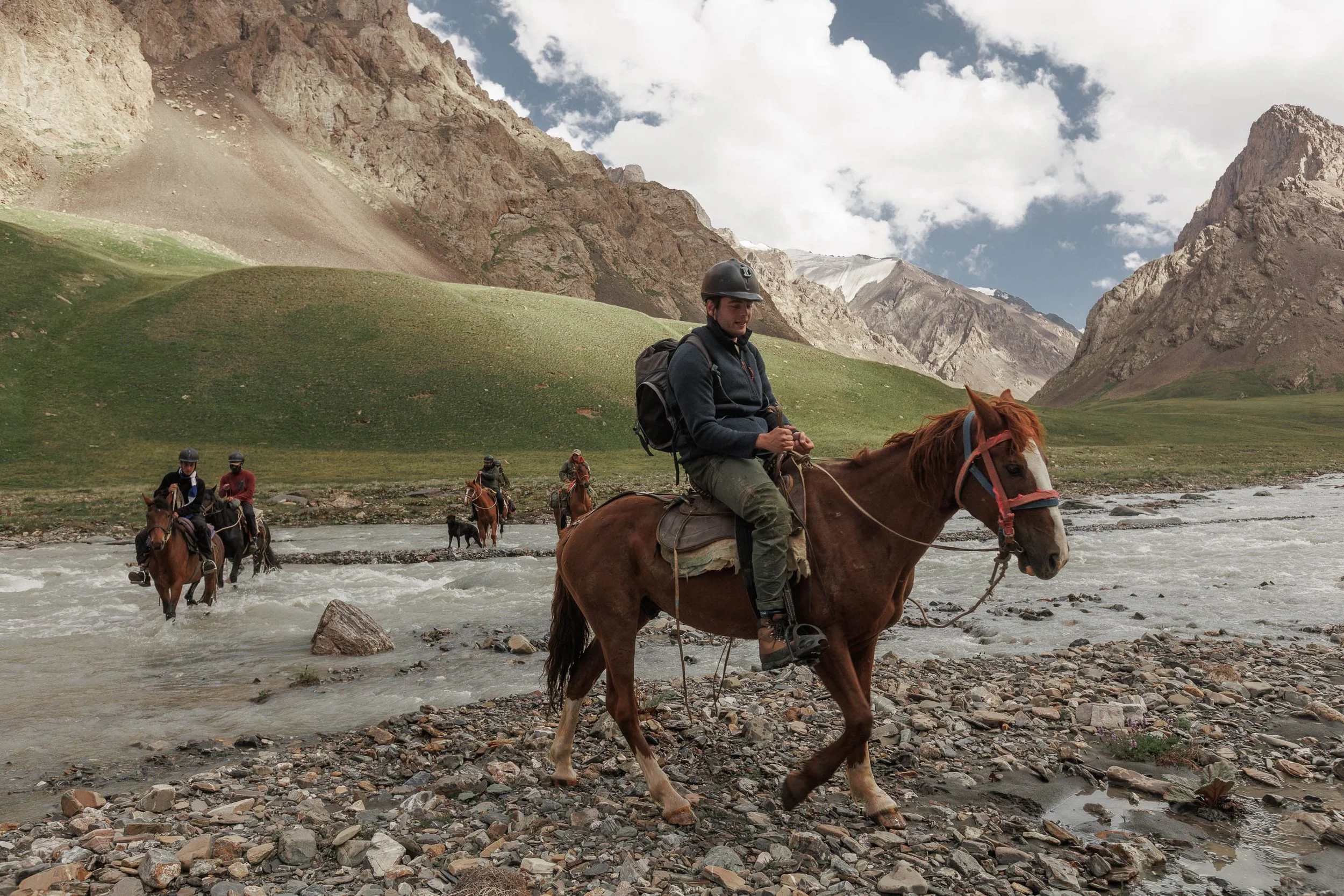Men crossing a river on horse back in Kryzgystan on a snow leoaprd tracking holiday