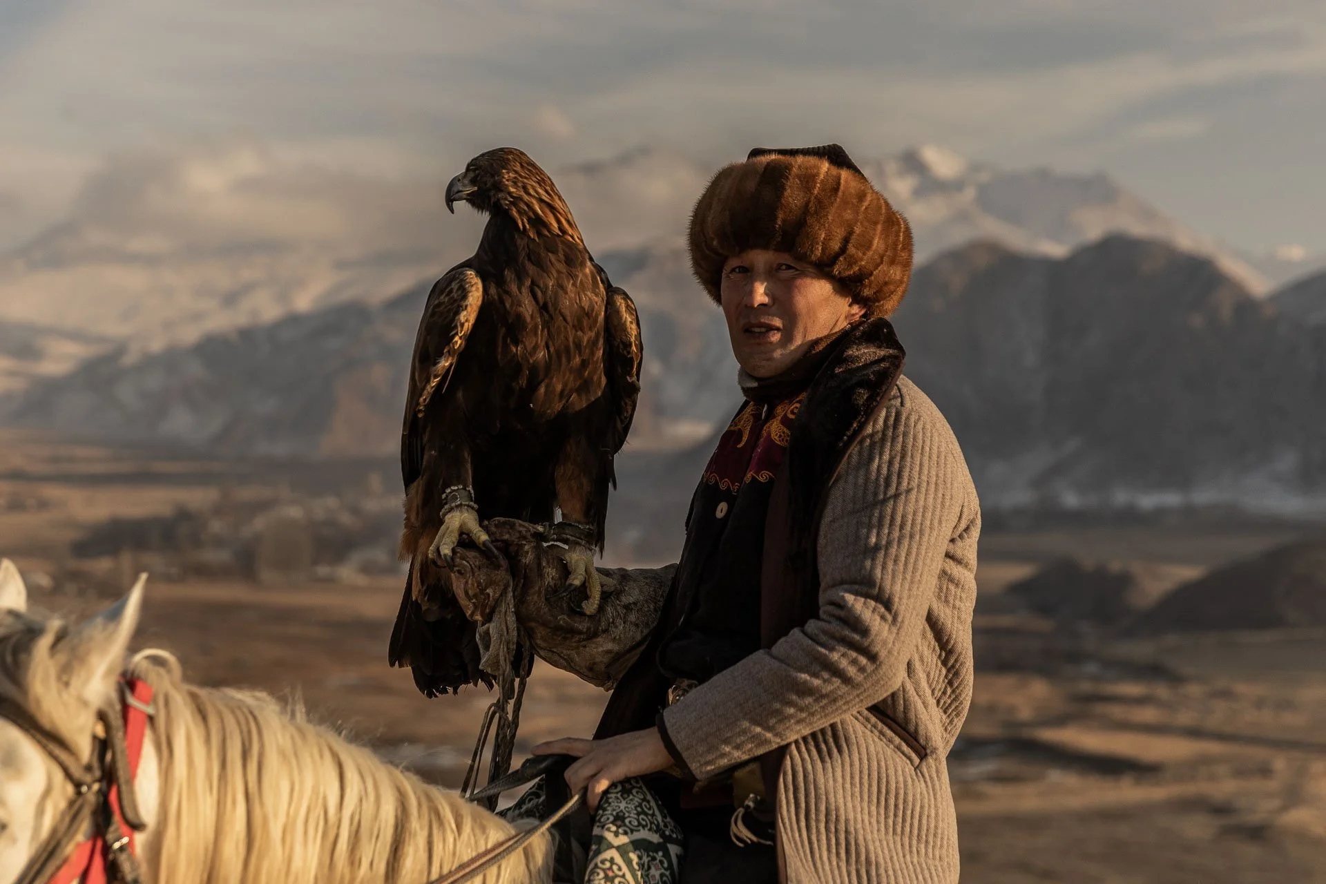 An eagle hunter on a white horse during a guided tour in Kyrgyzstan