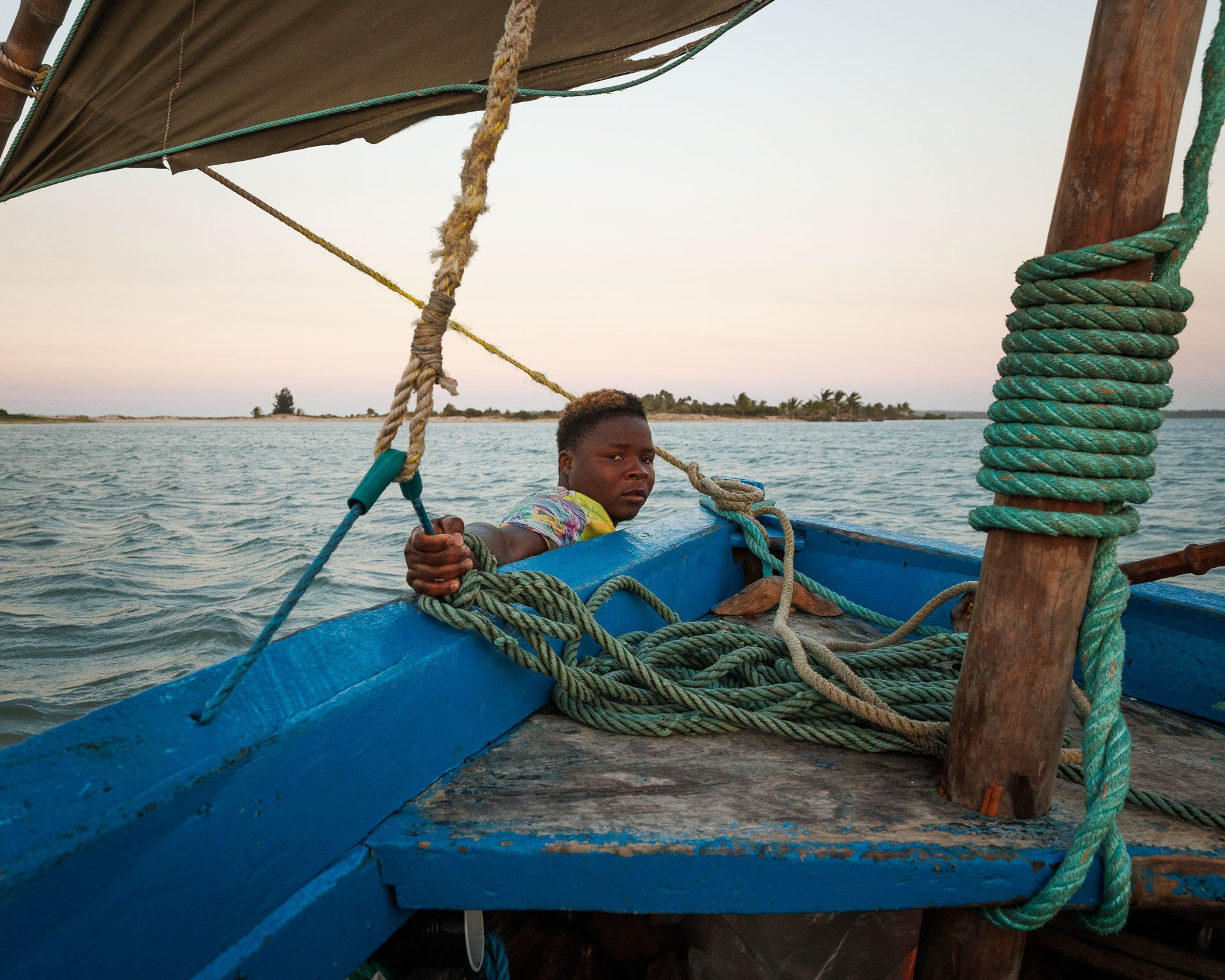 A young man next to a boat on a marine safari