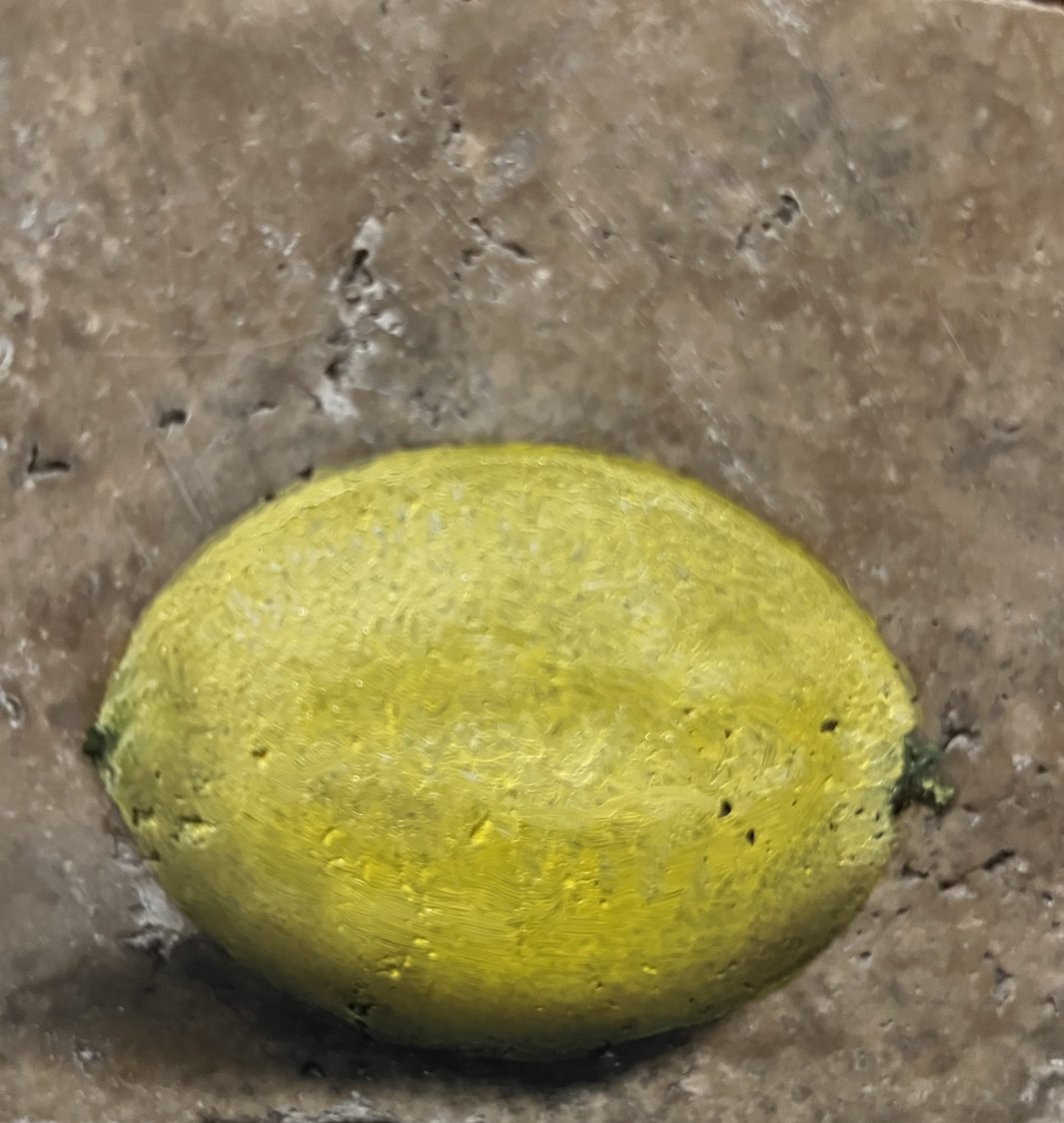 Close-up image of a yellow tennis ball resting on a concrete surface.