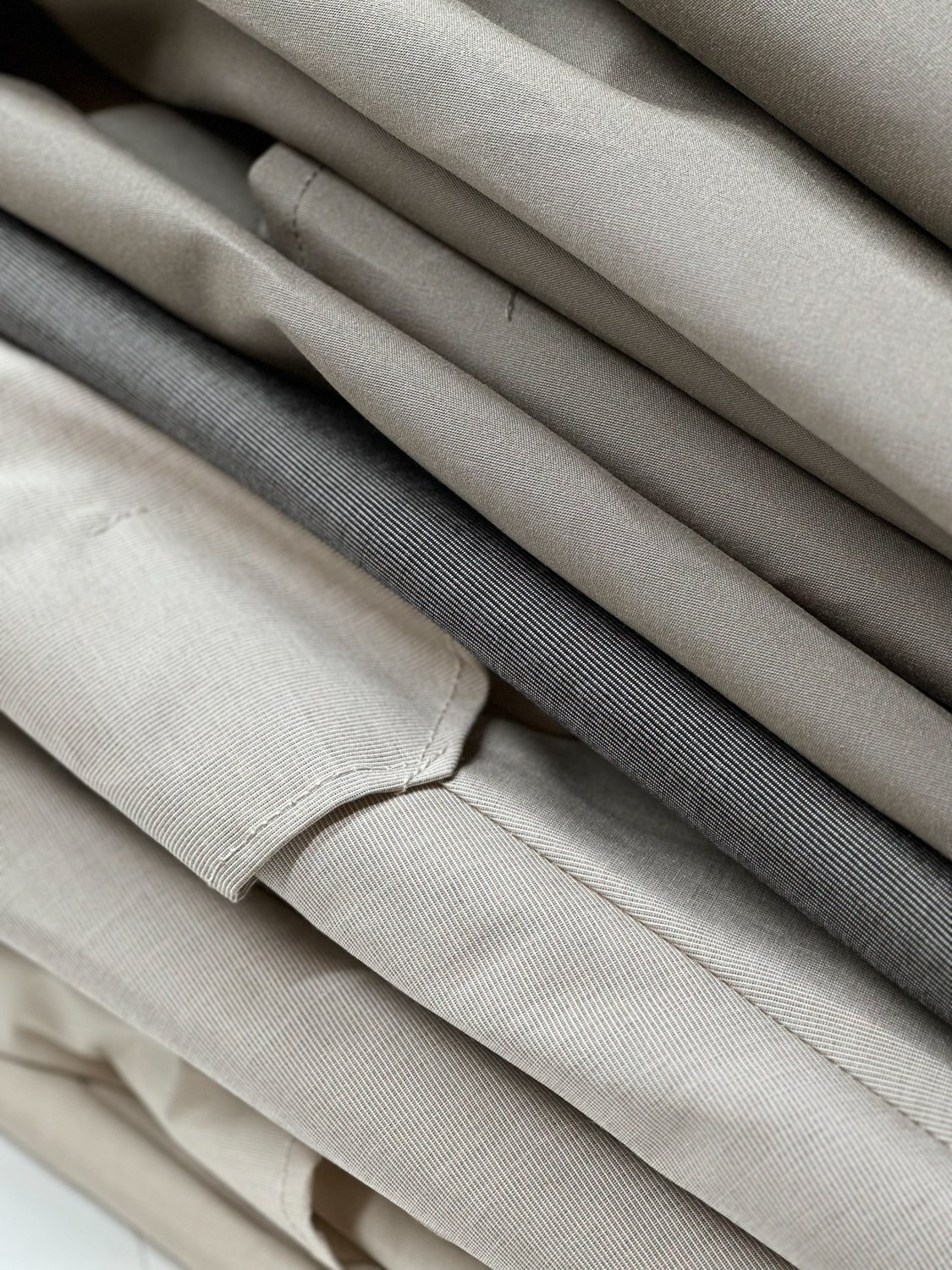 Verschiedene Stoffe für Bespannungen von Sonnenschirmen in neutralen Tönen, übereinandergelegt, mit verschiedenen Texturen und Mustern.