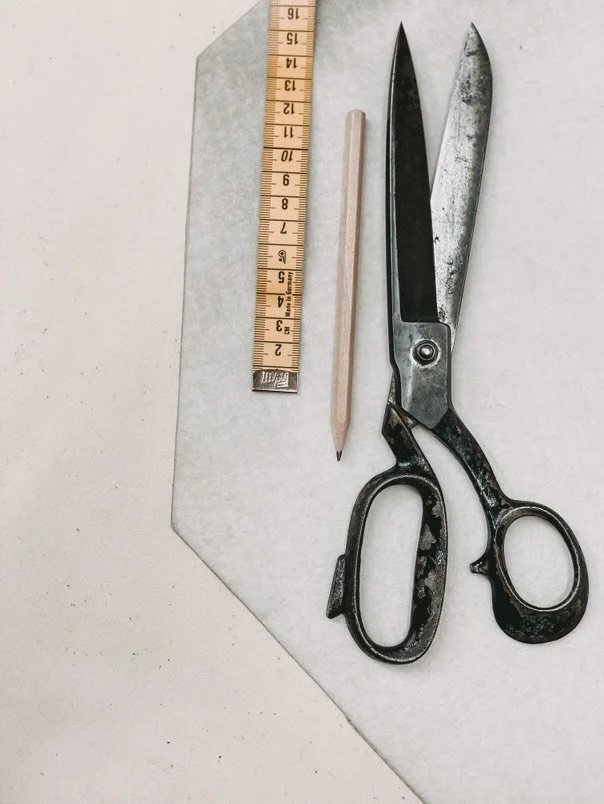 Schnittschere, Bleistift, Stoffband und Lineal auf weißem Untergrund in der Näherei von Chiemsee Schirme.