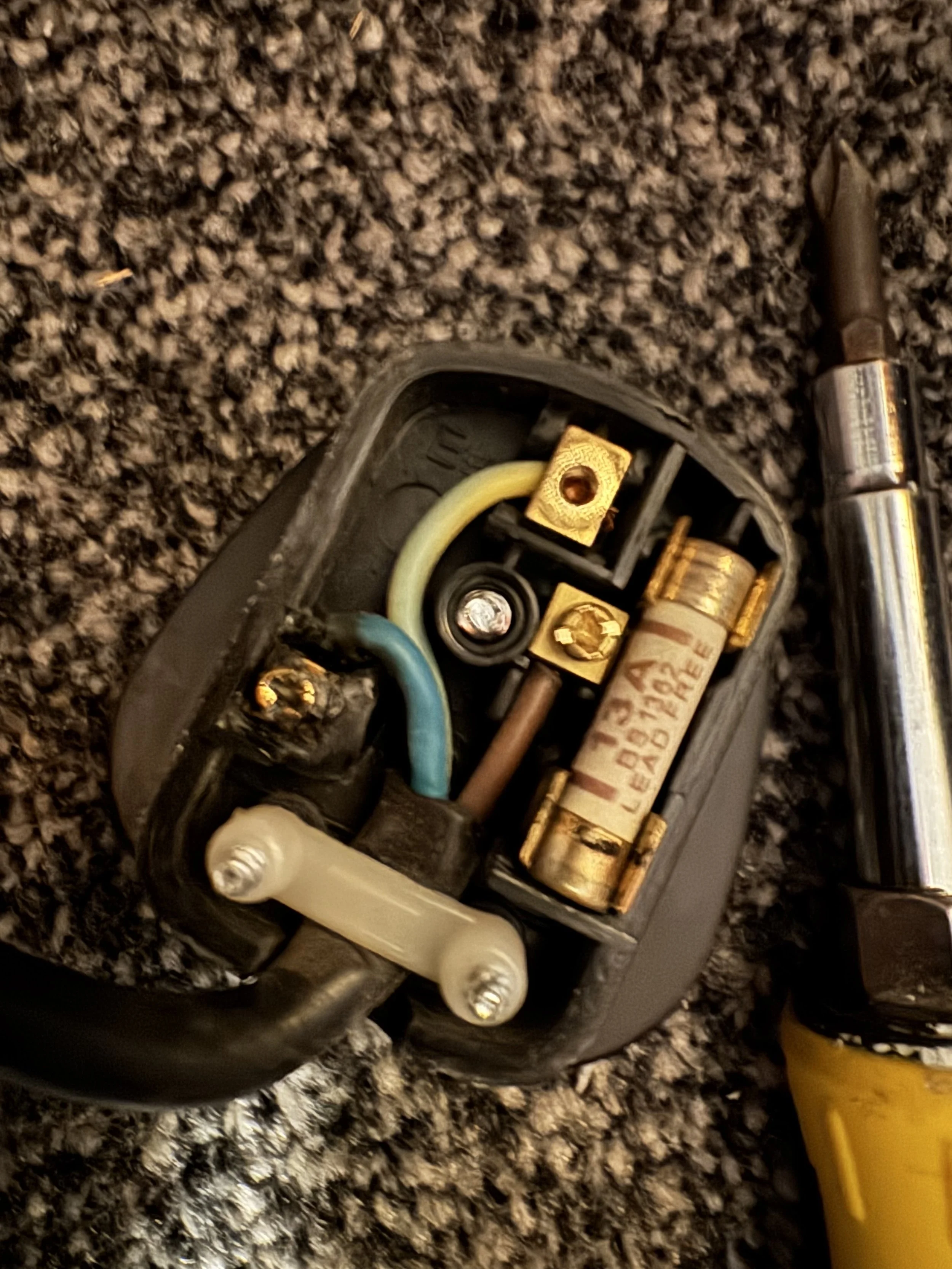 Close-up of the internal components of a power tool, including a battery and wiring, with a screwdriver nearby.