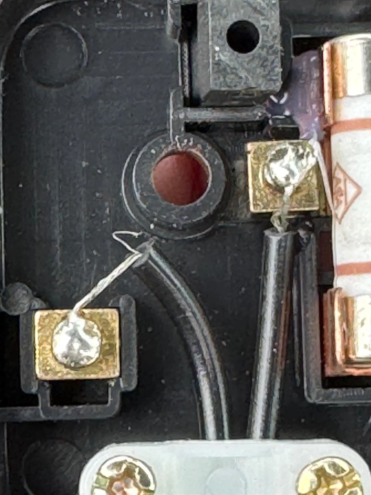 A close-up view of metalworking equipment, featuring a black countertop with two heated blocks and a small container of molten metal in the center, with a metal rod connecting the blocks.
