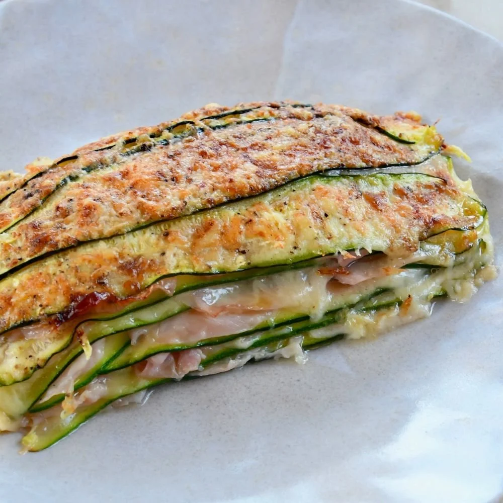 Una fetta di parmigiana di zucchine con formaggio, pomodoro e prosciutto.