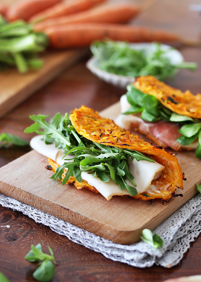 Sandwich con zucca, rucola e formaggio su un tagliere di legno.