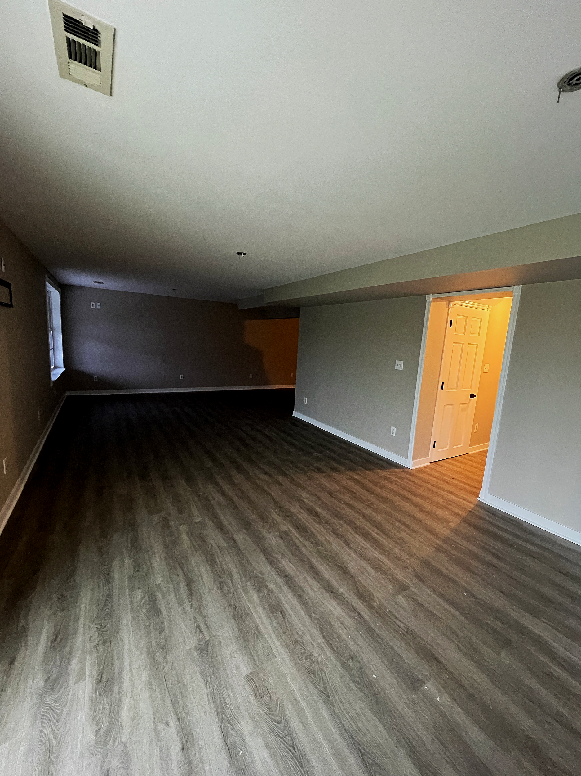 Basement with hardwood flooring and baseboards installed and walls painted